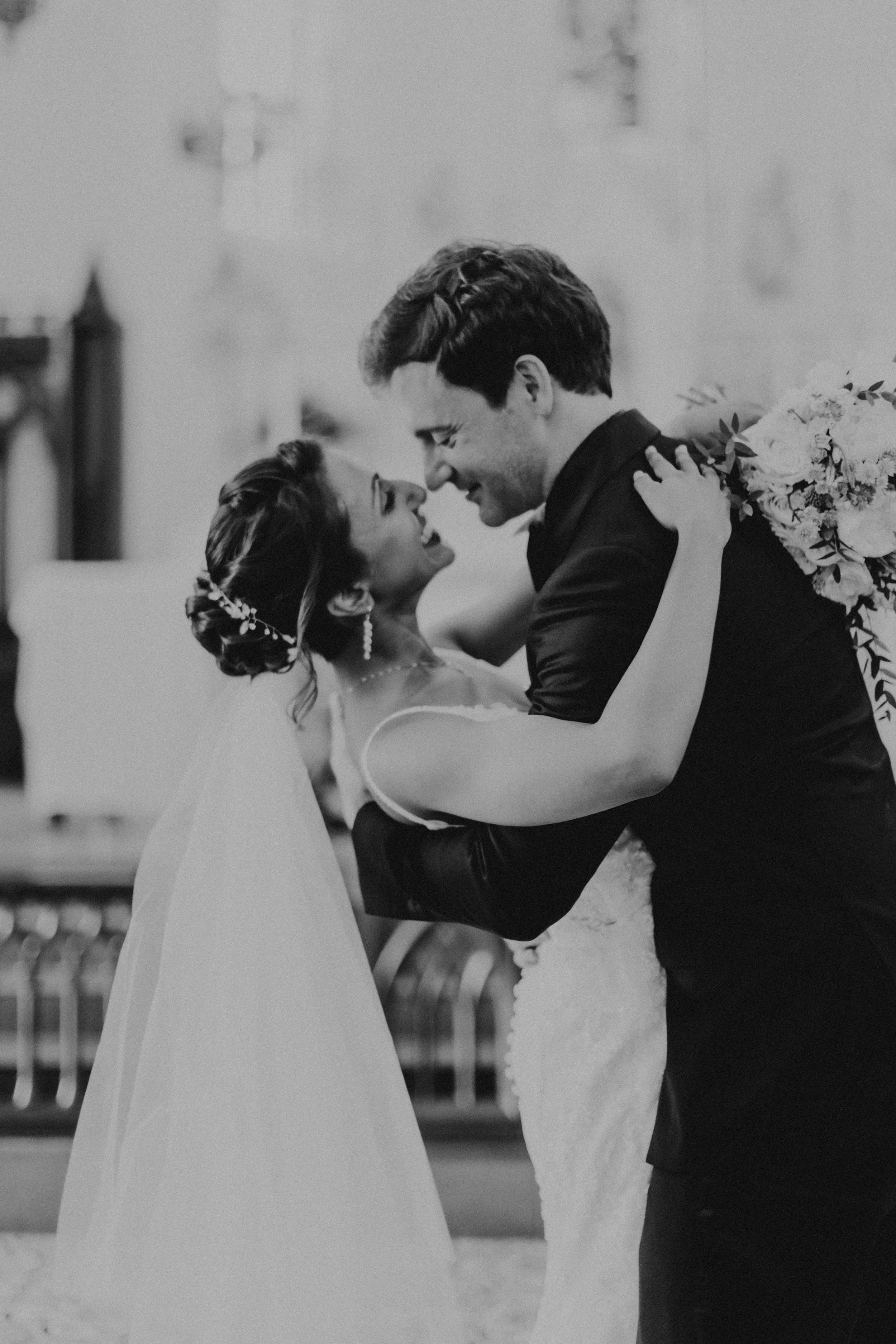 Cinematic black and white actual day church wedding photoshoot at Church of Saints Peter and Paul, this photo of the bride and groom sharing a romantic moment was captured by Ash for Breadandbutterworks.
