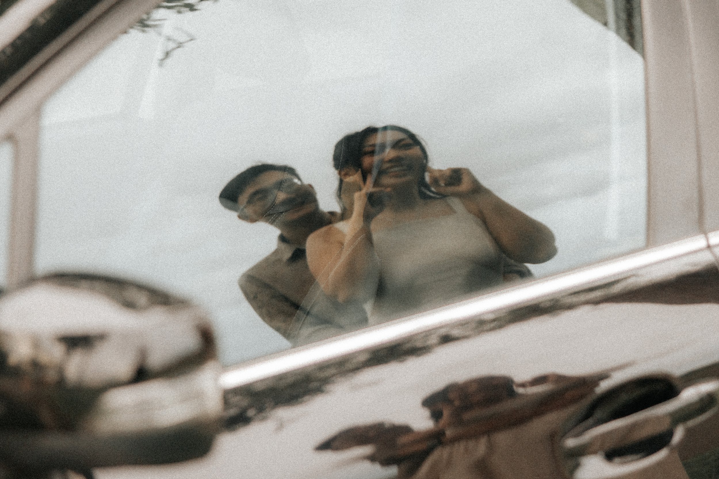 Artistic pre-wedding photo of a couple shot on a car door's reflection, captured by Breadandbutterworks in a soft and heartfelt style.