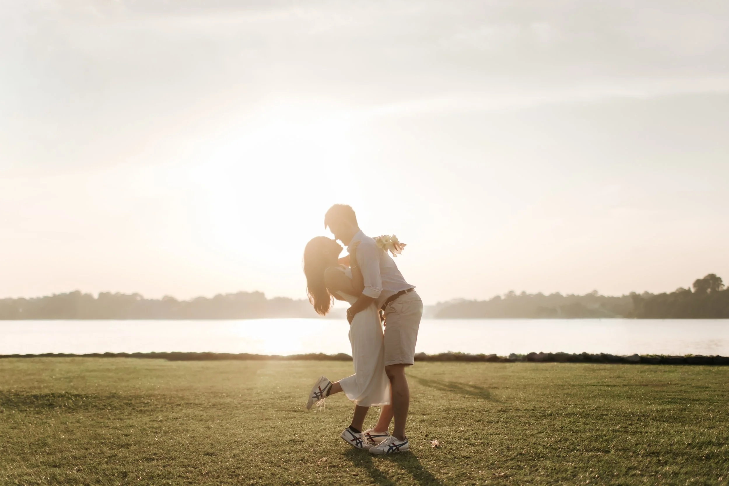 Romantic and airy pre-wedding photoshoot at Upper Seletar Reservoir, the couple is hugging in this intimate shot with the sunset in the background. Captured by Arielle from Breadandbutterworks.