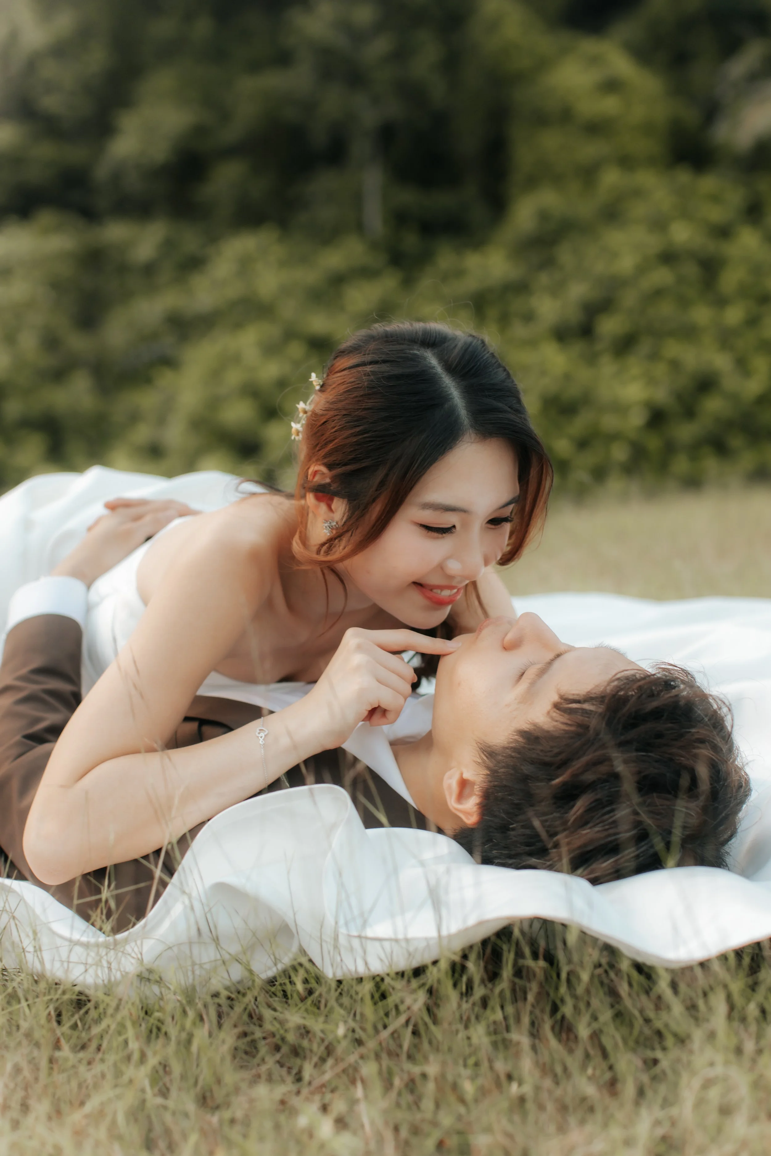 Romantic and cute pre-wedding photoshoot at Canterbury Hill. The bride lays on top the groom as she teases him cheekily. Captured in a light and airy style by Arielle from Breadandbutterworks.