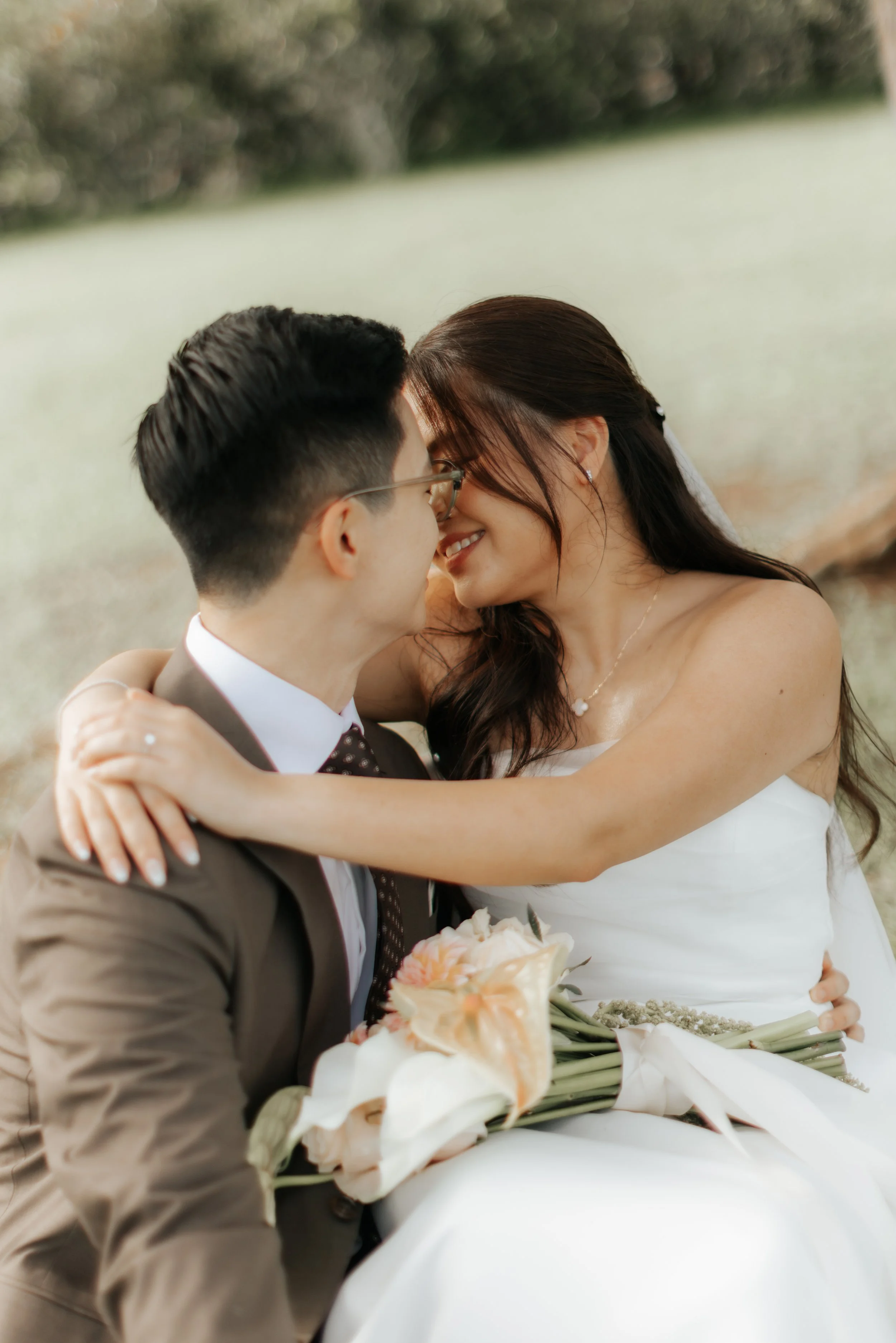 A couple enjoys a moment of quiet intimacy during their actual day wedding in a park. The light and airy vibes was captured by Breadandbutterworks.