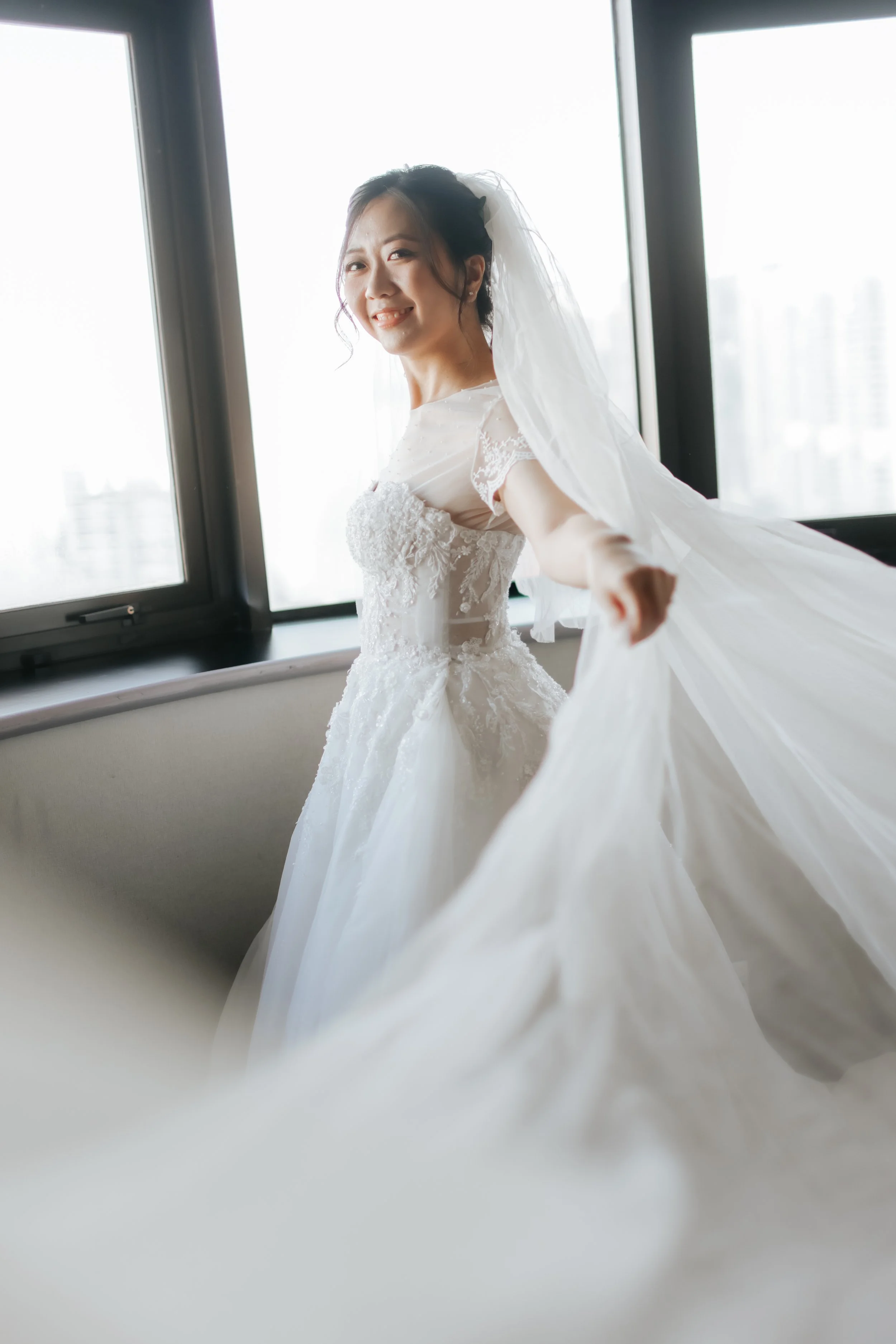 Artistically shot photo of a bride on her actual wedding day moments after she has put on her wedding gown. She twirls for the camera as the train of her gown and her veil flows towards the camera gracefully. Captured by Arielle for Breadandbutterwor