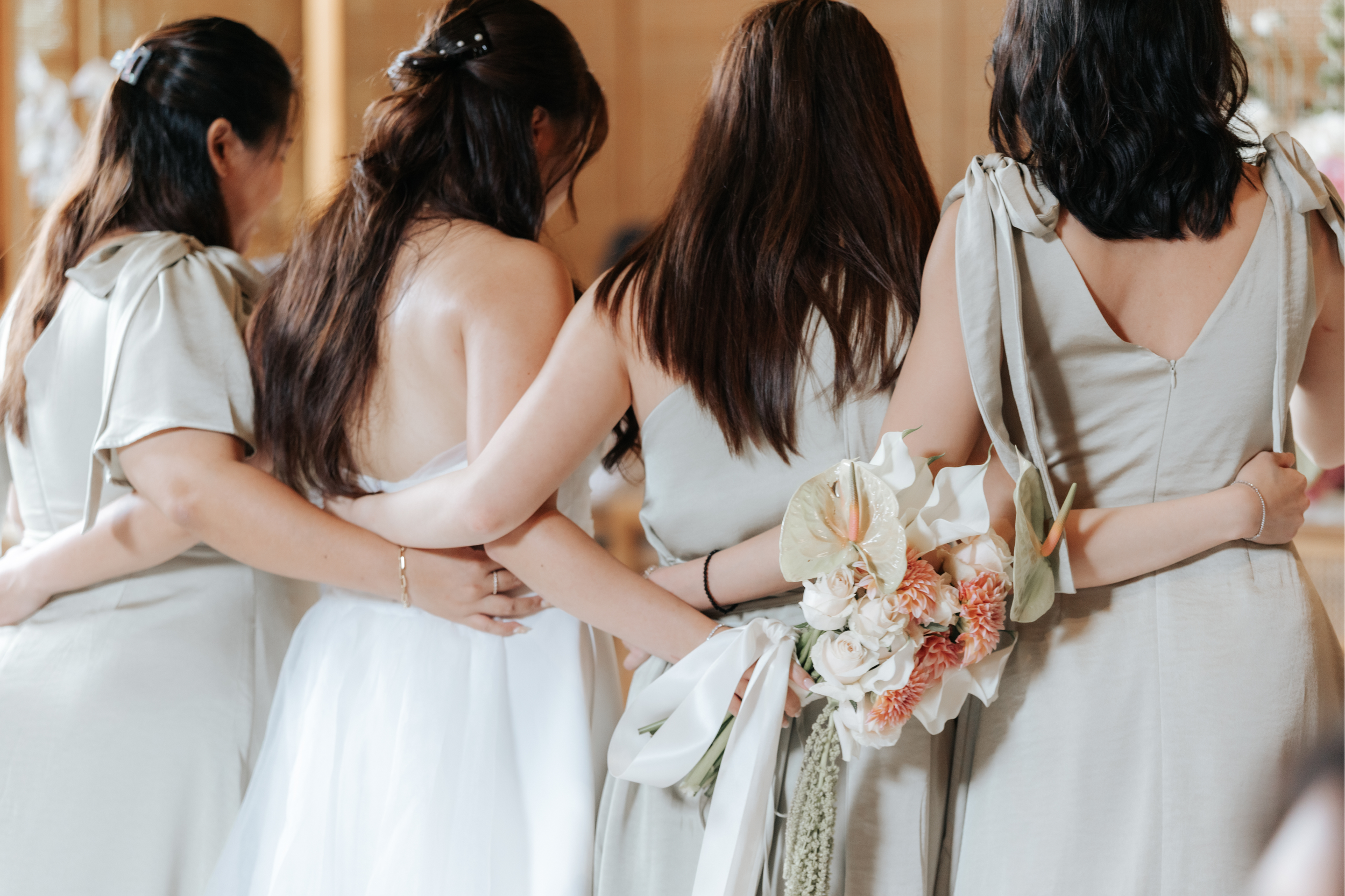 The bride and her bridesmaids are captured from behind in a quiet and meaningful moment during the actual day wedding. This moment was captured by Breadandbutterworks.