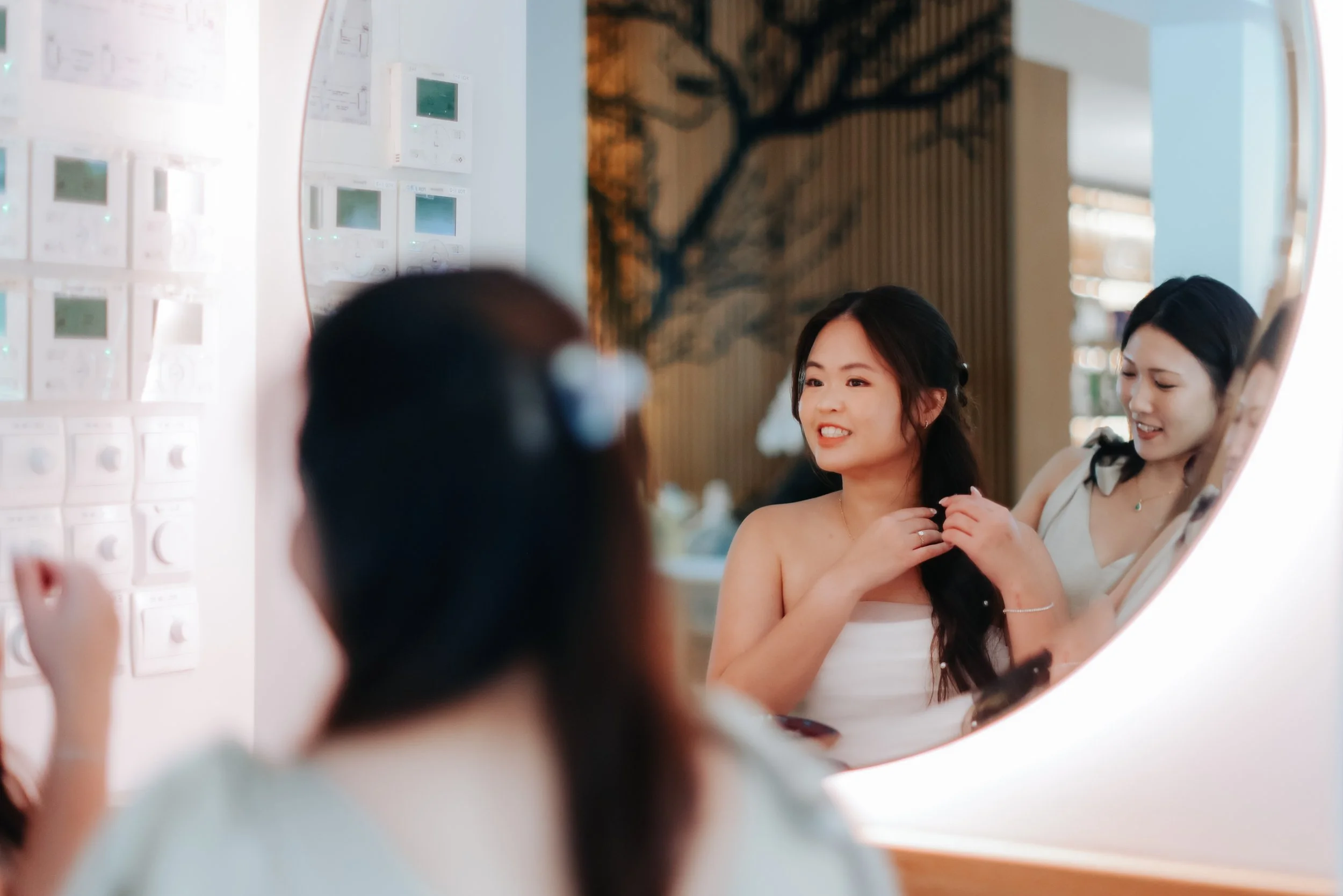 A bridesmaid is attending to the bride in the middle of the wedding ceremony. The photo is captured as a reflection from a mirror by Breadandbutterworks.