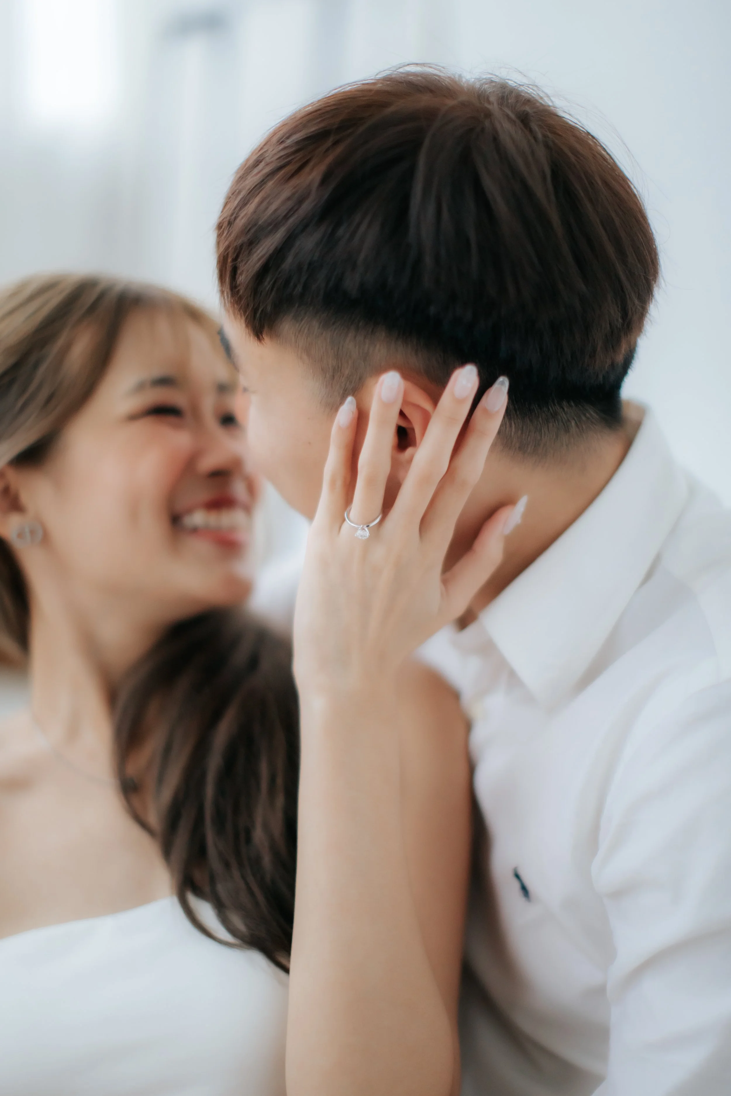 Light and airy proposal photo of a couple sharing a close romantic moment, with the bride showing her engagement ring in Singapore.