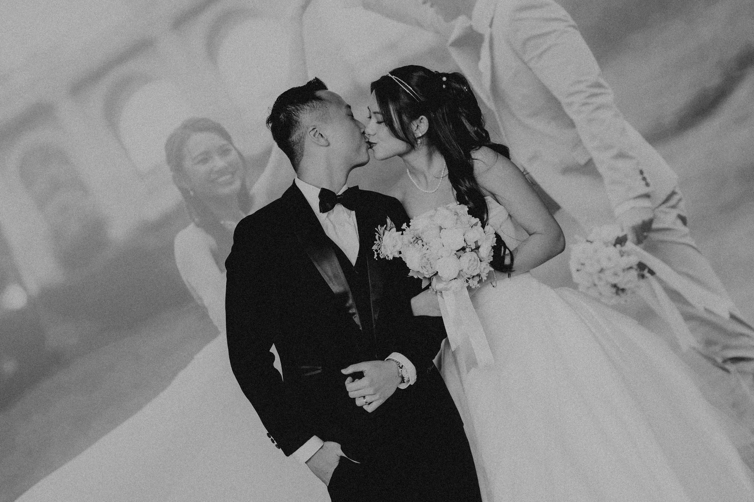 Cinematic black and white actual day wedding photography of couple sharing a kiss, captured by Breadandbutterworks.