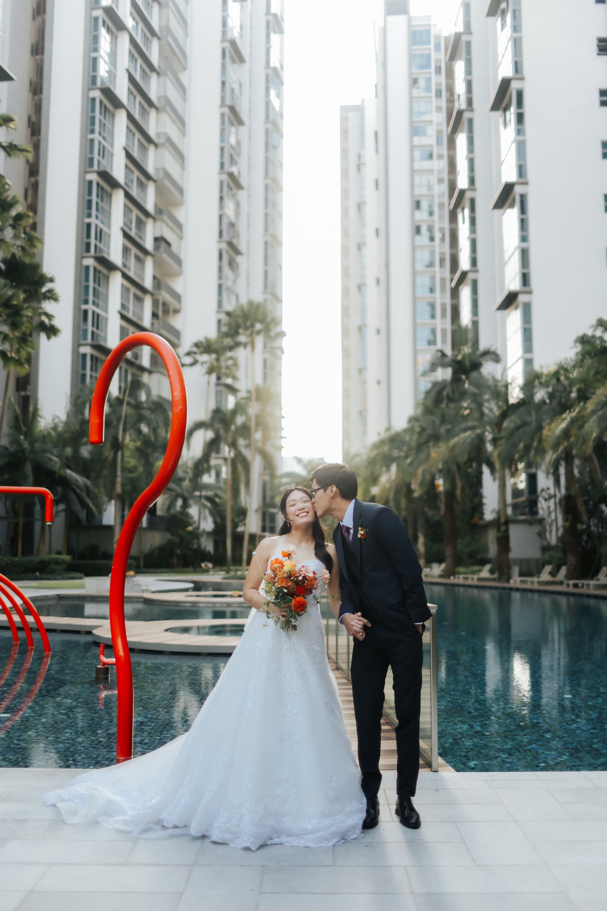 Actual day wedding shoot of a couple posing for a photo at the swimming pool area of their condominium home. Captured in a light and airy style by Arielle for Breadandbutterworks.
