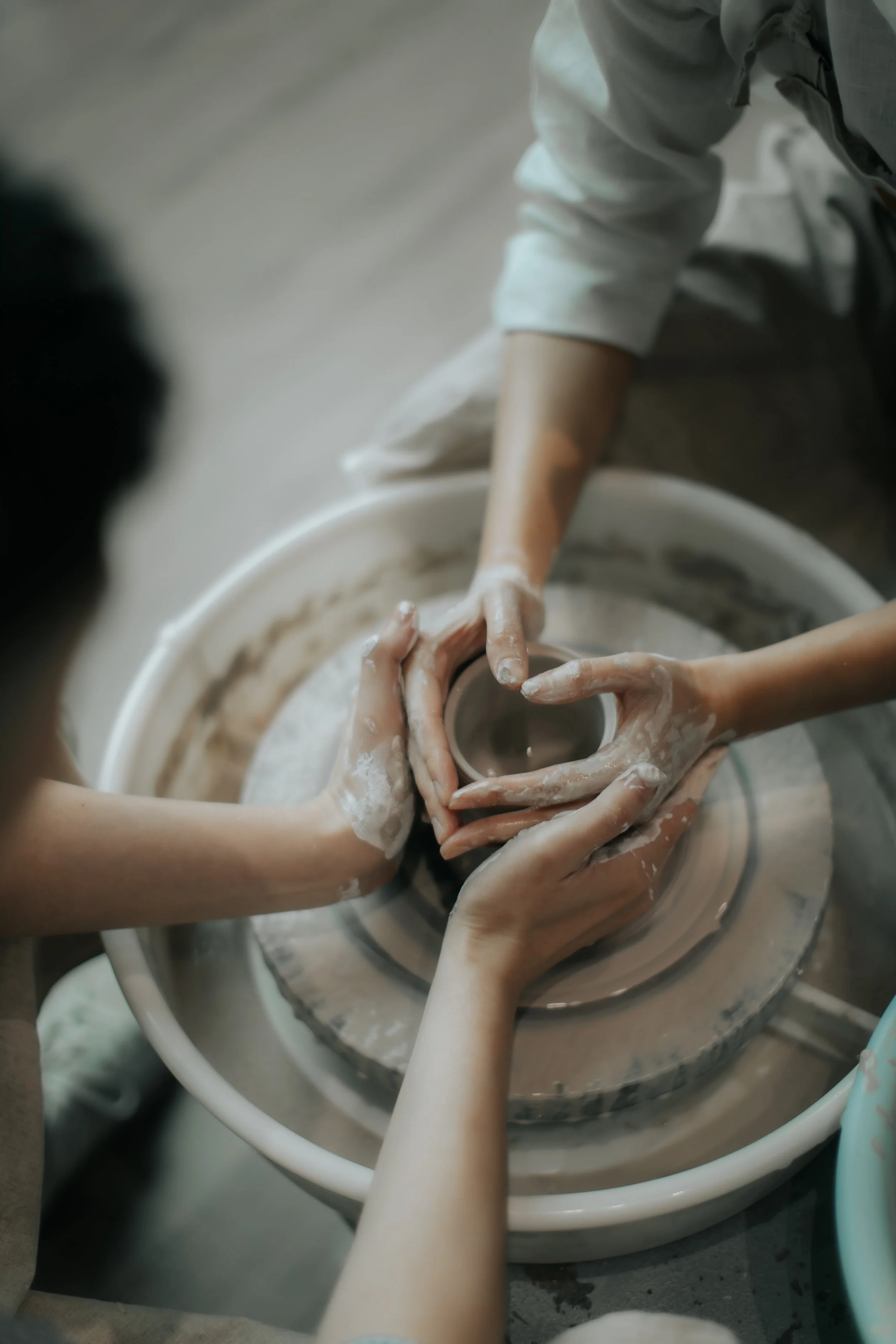 Creative intimate pre-wedding photoshoot at a pottery studio in Singapore (Tao Pottery), the couple is working on a pottery wheel in a romantic fashion. Captured in the light and airy style of Breadandbutterworks.
