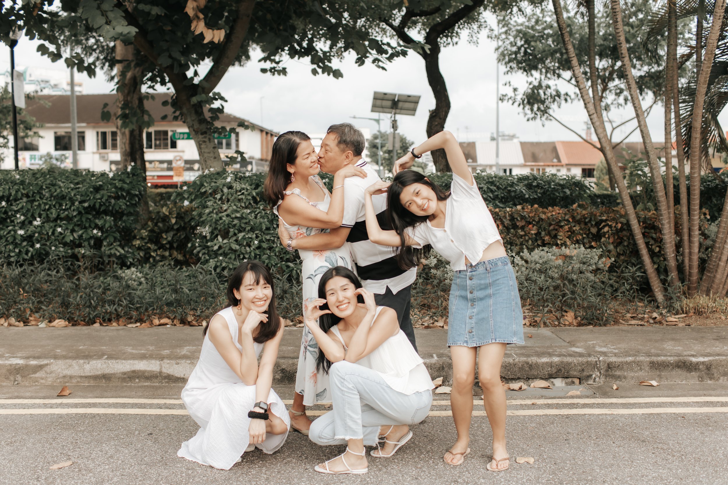 Heartwarming family photoshoot in Singapore featuring a family posing by the road, captured in a light and airy style by Arielle for Breadandbutterworks.