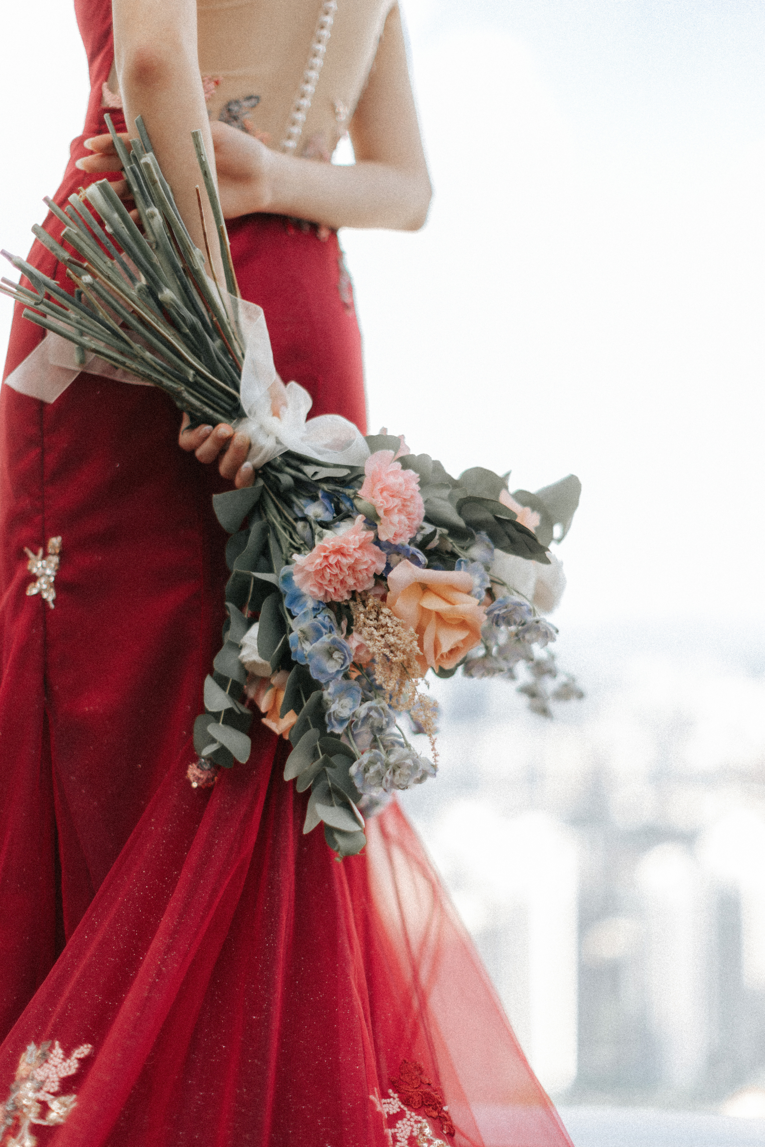 Wedding gown and bouquet detail shot of the bride on her actual wedding day. Her gown is a red oriental styled dress that is regal and elegant. Photographed by Breadandbutterworks.