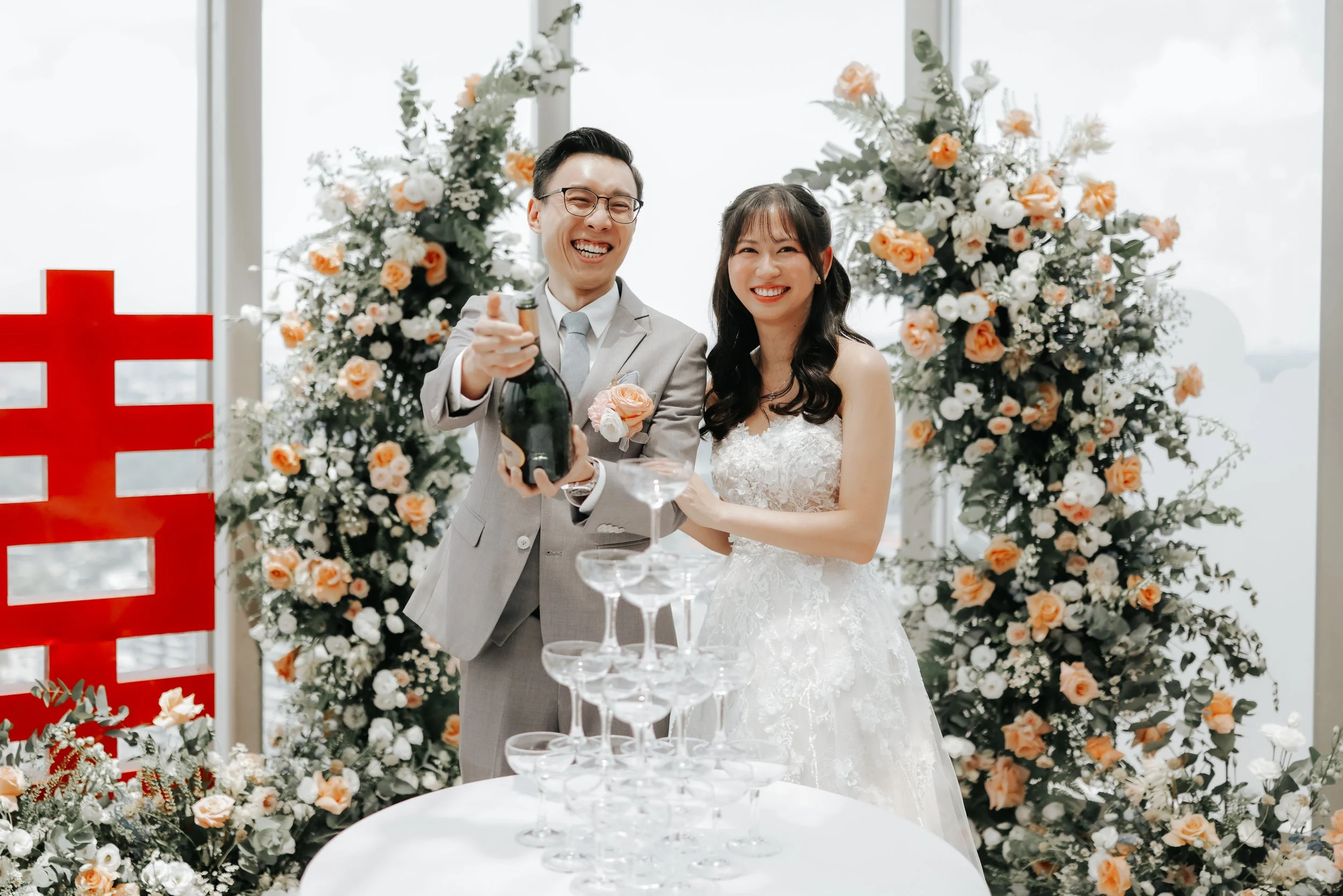 The couple happily poses for a photo during their actual day wedding right after popping a bottle of champagne. Photographed by Breadandbutterworks.