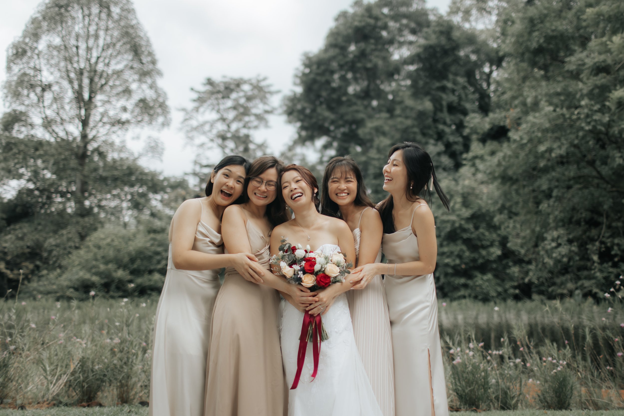 Light and airy actual day wedding photoshoot of the bride and her bridesmaids with a background of greenery. Captured by Arielle for Breadandbutterworks.