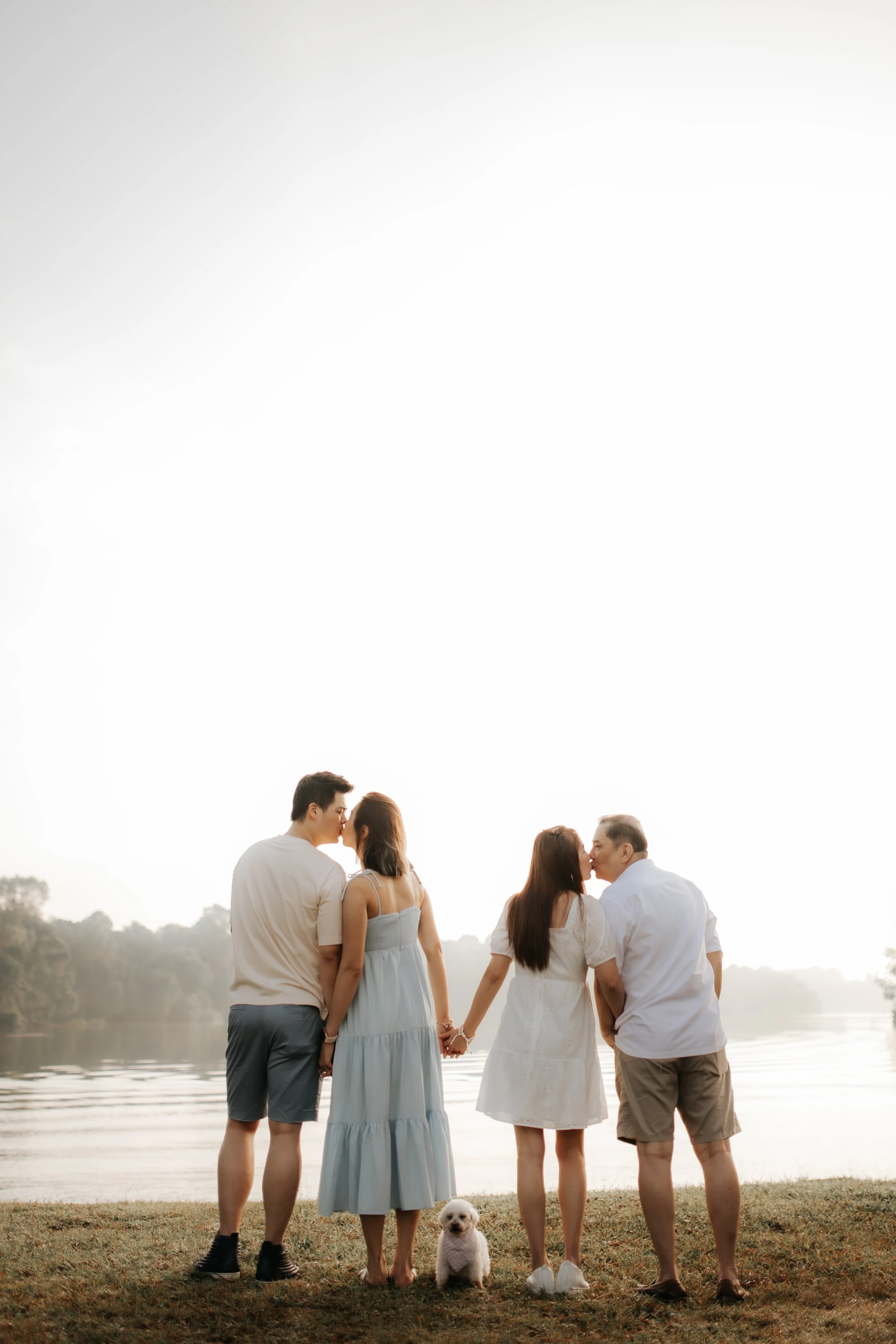 Light and airy family photoshoot in Singapore featuring a family posing for a photo with their pet dog, captured by Breadandbutterworks.