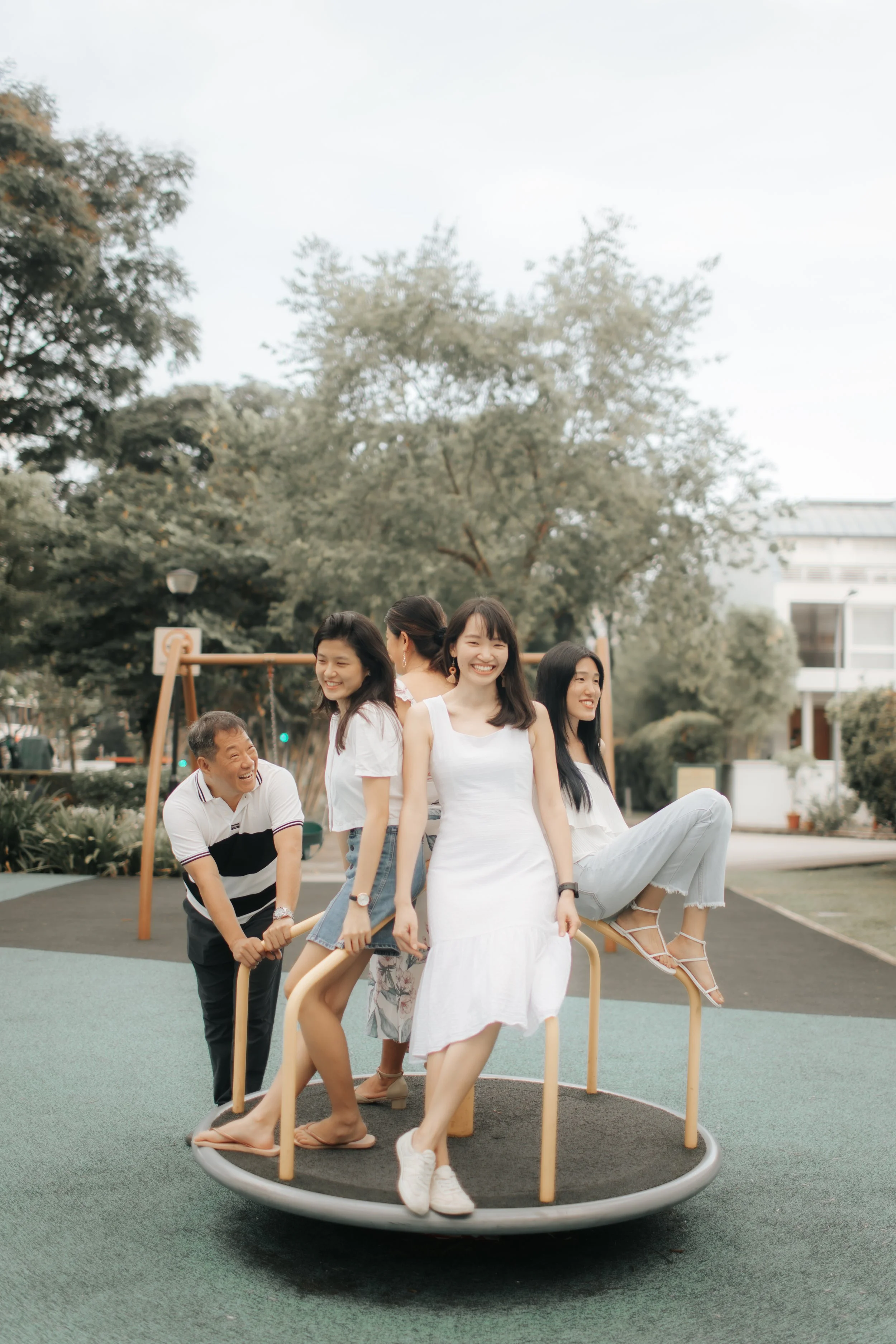 Heartwarming family photoshoot in Singapore featuring a family posing in a playground, captured in a light and airy style by Arielle for Breadandbutterworks.