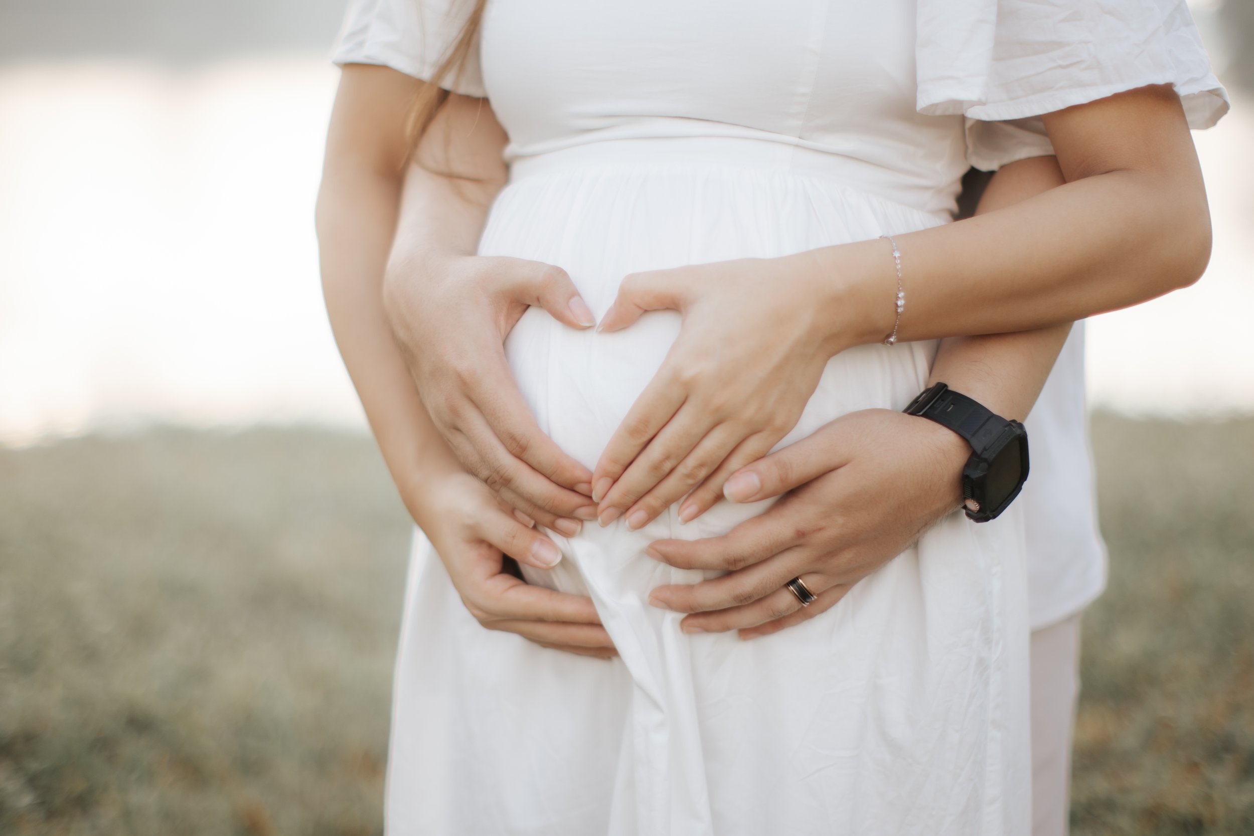Warm and romantic maternity photoshoot of the expecting couple posing using the pregnant mother's belly, taken at Upper Peirce Reservoir. Captured by Breadandbutterworks in a light and airy style.