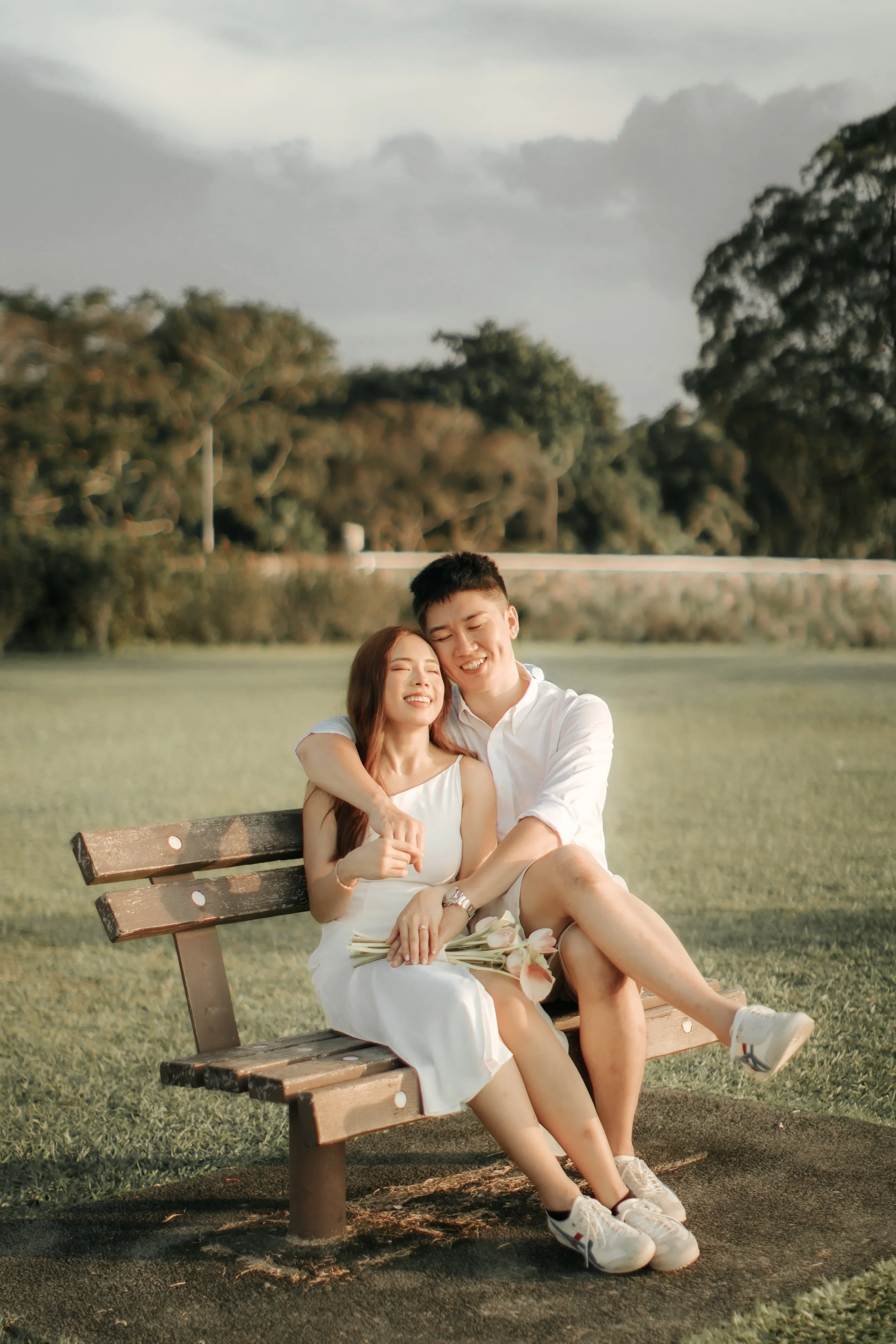 Romantic and airy pre-wedding photoshoot at Upper Seletar Reservoir, the couple is relaxing on a bench. Captured by Arielle from Breadandbutterworks.