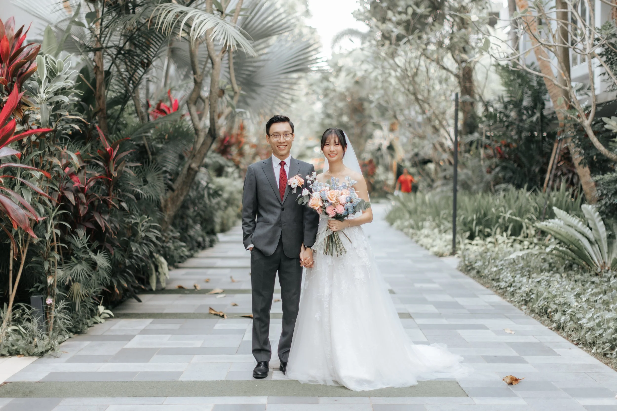 The couple poses along a garden-flanked path on their actual wedding day, moments before heading to their wedding. Photographed by Breadandbutterworks.