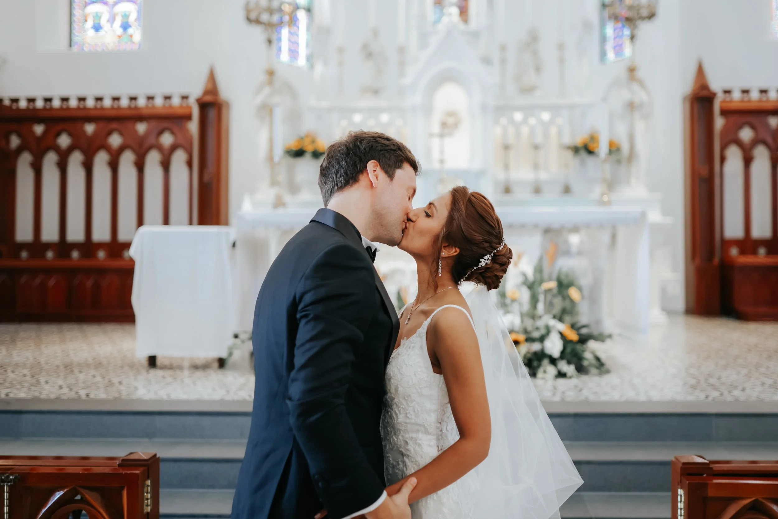 Light and airy actual day church wedding photoshoot at Church of Saints Peter and Paul, the couple shares a romantic moment in front of the lectern captured by Ash for Breadandbutterworks.