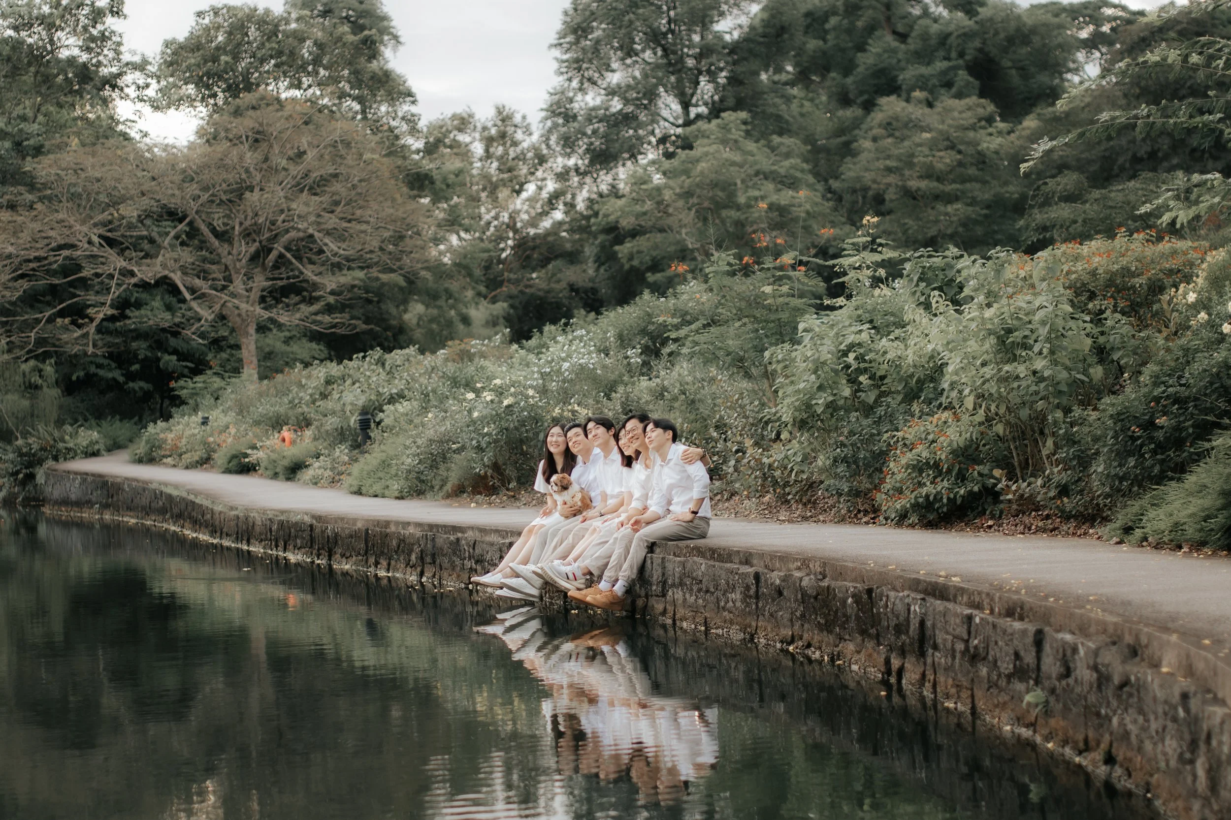 Cover image for Ash’s family and maternity photography collection, featuring a family sitting together by the water in a Singapore park.