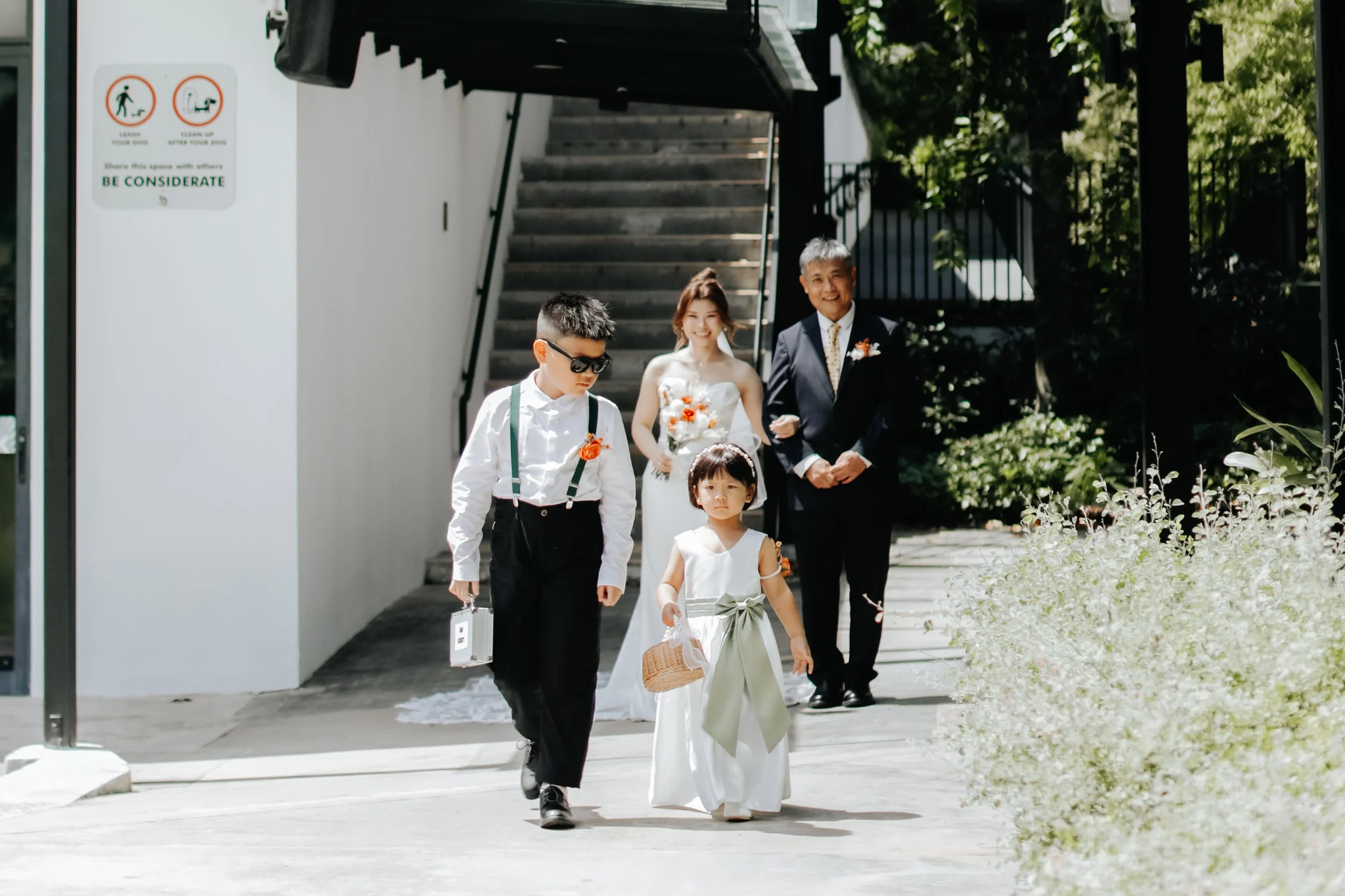 Light and airy actual day wedding photoshoot at Canopy HortPark, the bride and her father walk behind the flower children on their way to the wedding. Captured by Arielle from Breadandbutterworks.