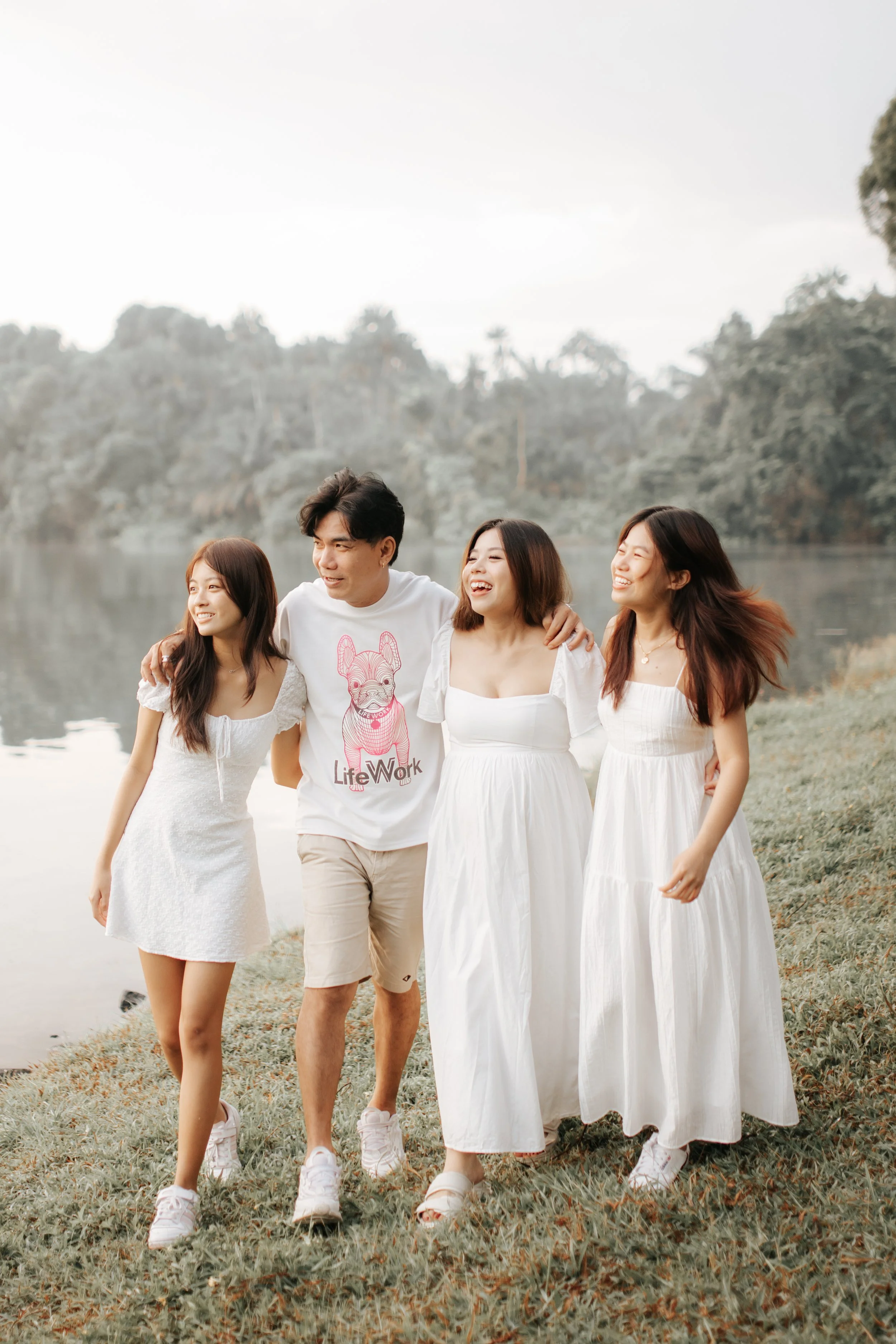 Warm and candid family photoshoot of a father and his three daughters, taken at Upper Peirce Reservoir. Captured by Breadandbutterworks in a light and airy style.