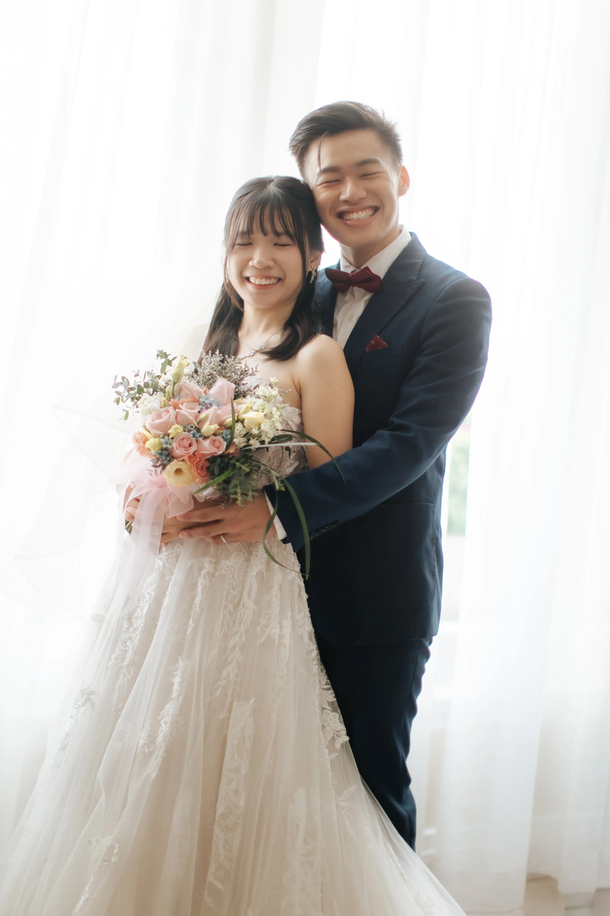A bride and groom on the actual wedding day posing for a loving photoshoot in their hotel suite before they head to the banquet. Captured in a light and airy style by Arielle for Breadandbutterworks.