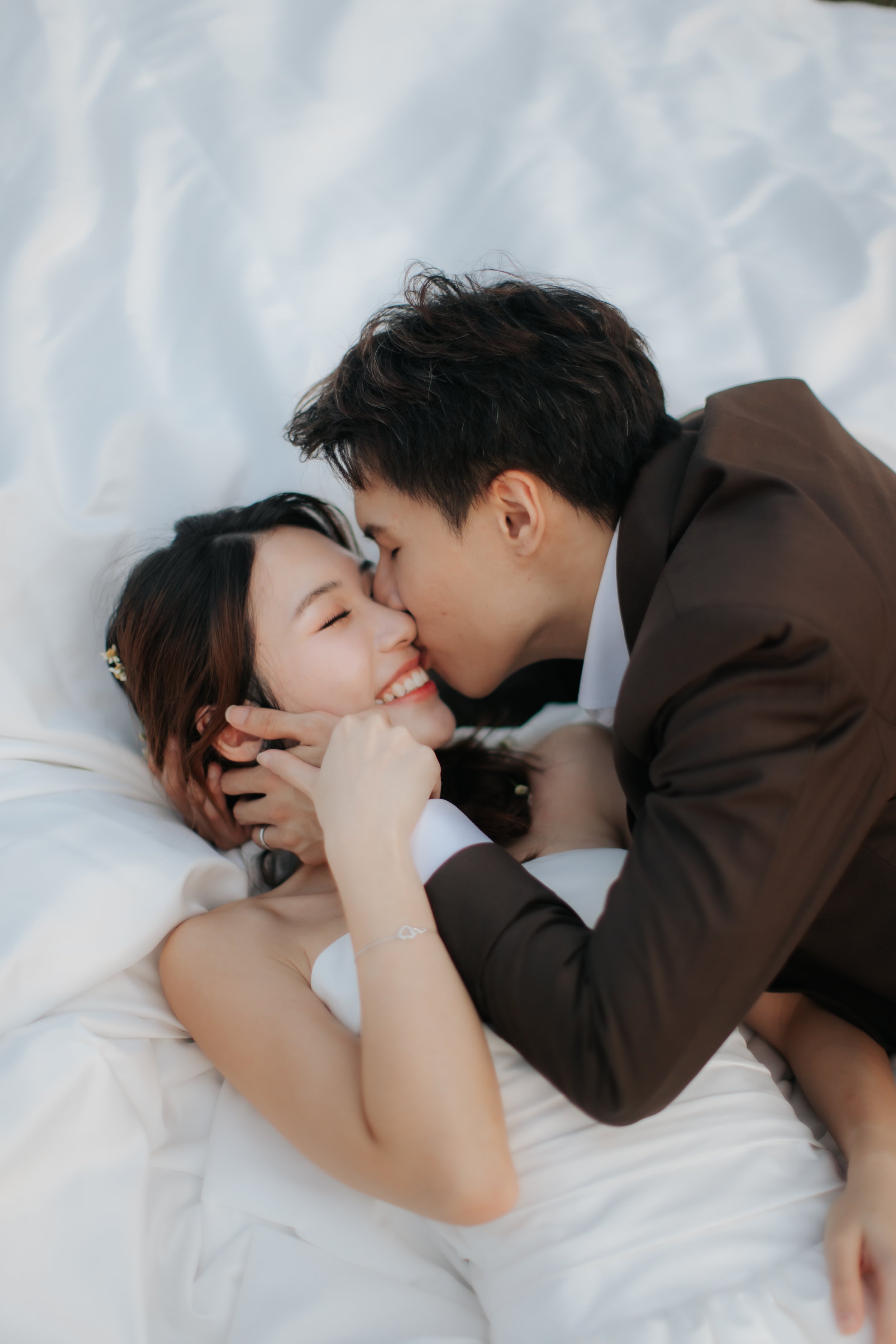 Romantic and dynamic pre-wedding photoshoot at Canterbury Hill. The couple rests on the ground and they are framed by the bride's gown. Captured in a light and airy style by Arielle from Breadandbutterworks.