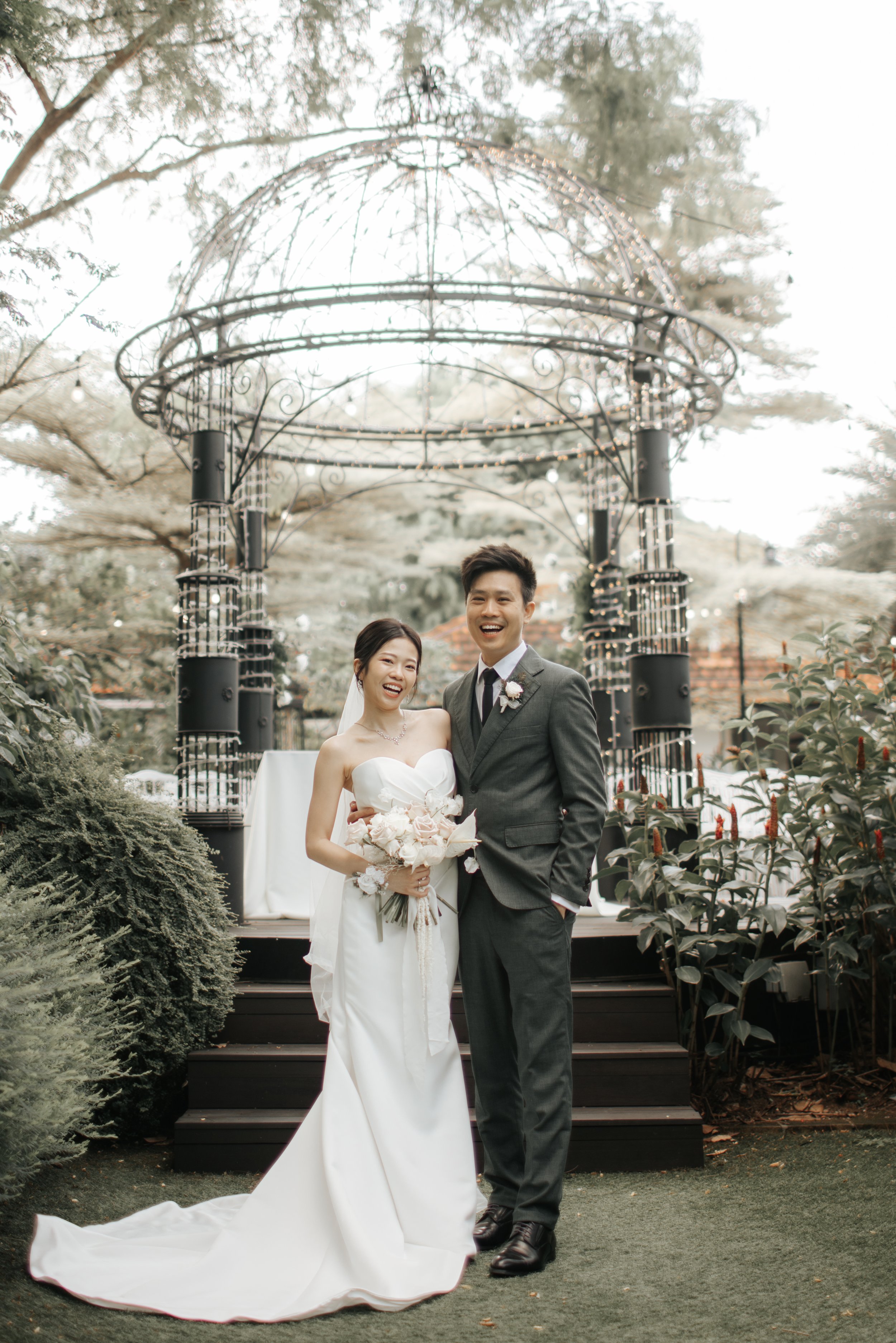 Light and airy actual day wedding photoshoot at the Summerhouse in Singapore of the couple posing in front of a gezabo. Captured by Arielle for Breadandbutterworks.