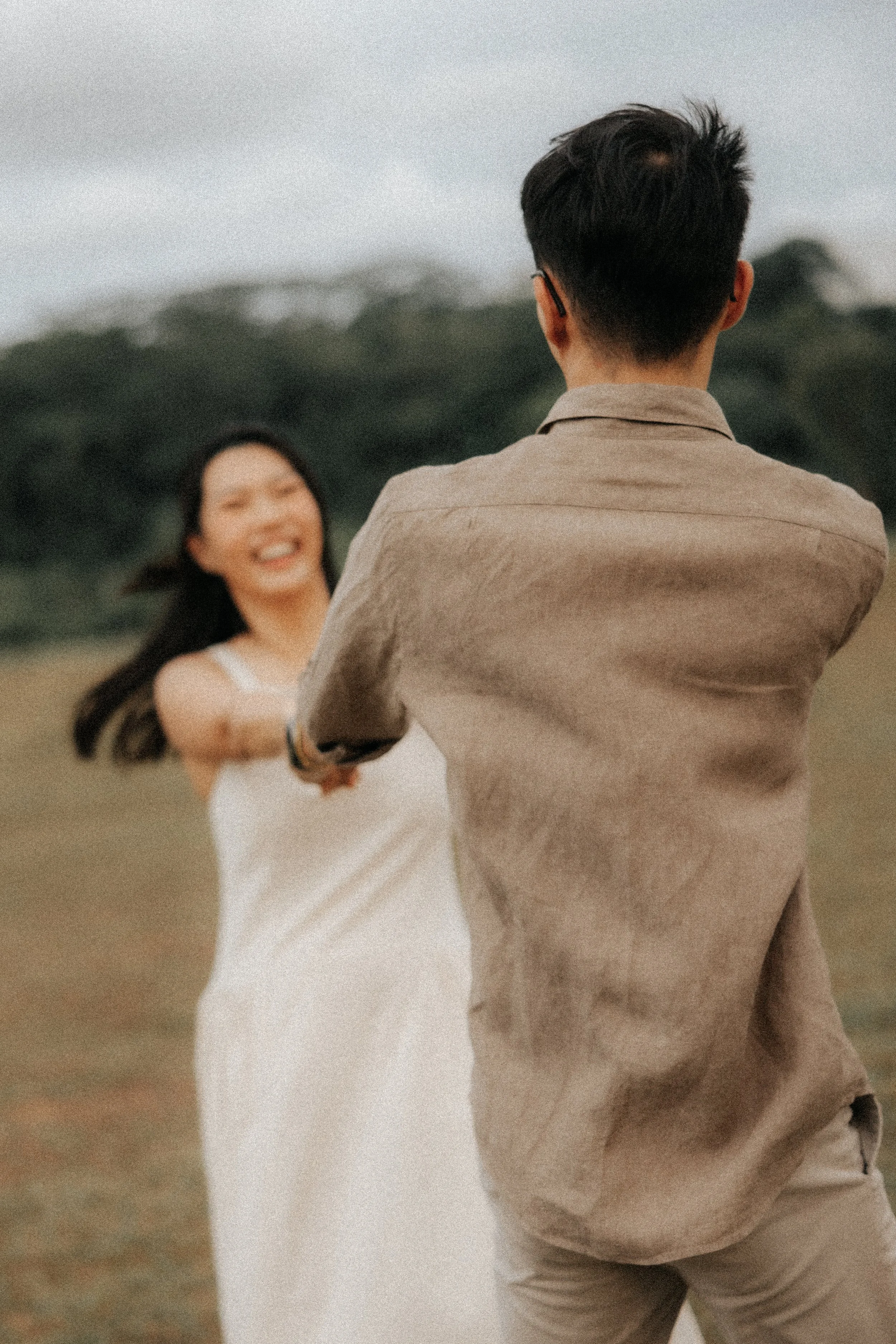 Artistic and playful pre-wedding photo of a couple having fun together at East Coast Park, captured by Breadandbutterworks in a soft and heartfelt style.