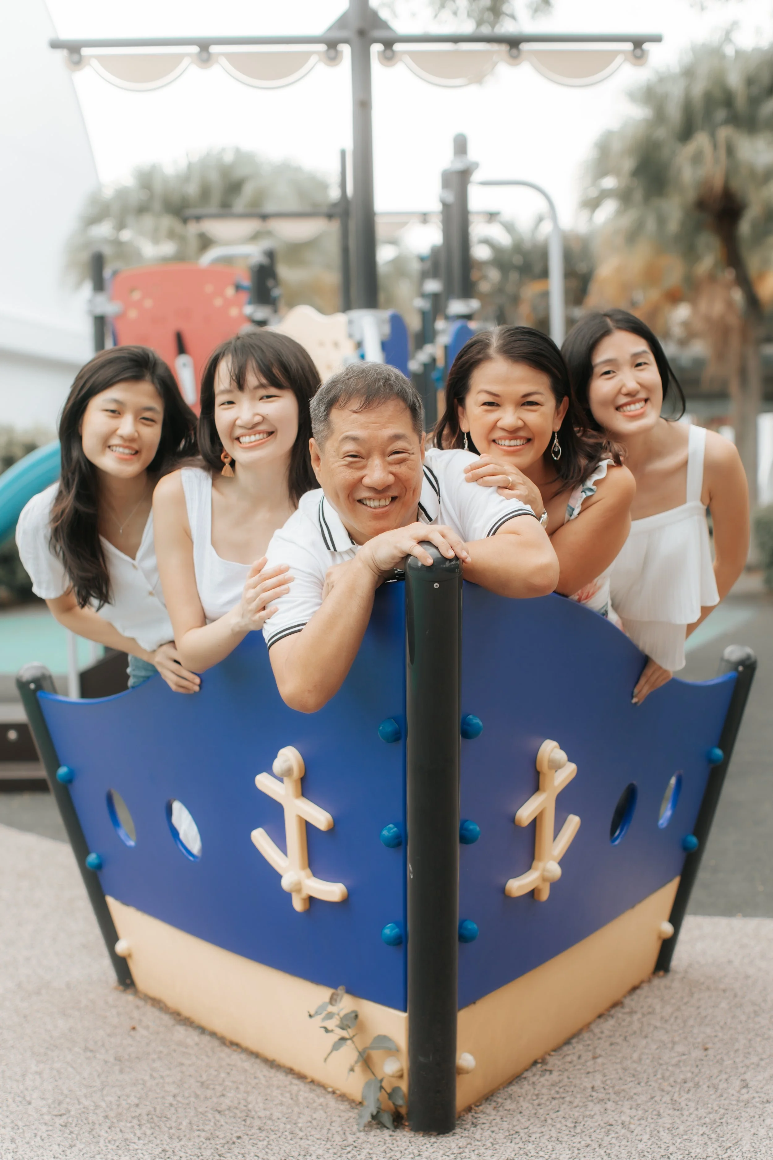 Heartwarming family photoshoot in Singapore featuring a family posing in a playground, captured in a light and airy style by Arielle for Breadandbutterworks.