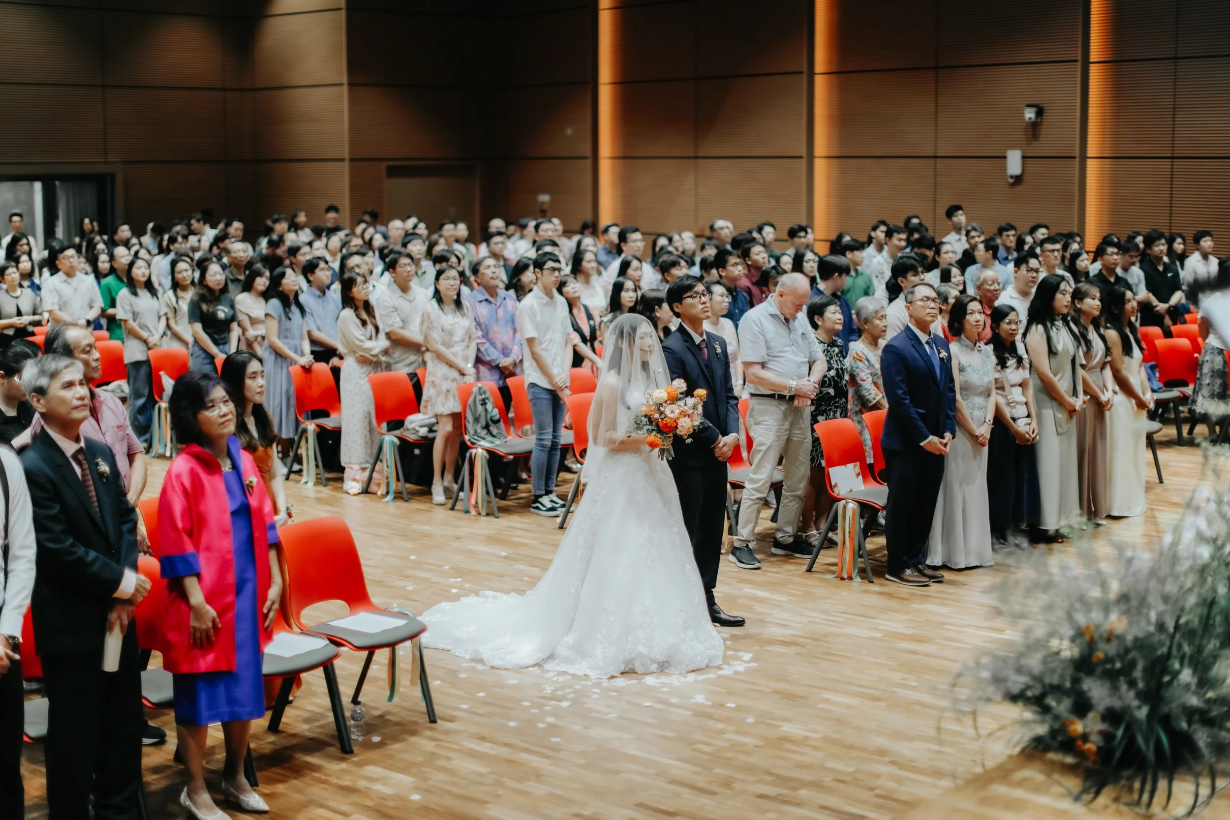 Actual day wedding shoot of the bride and groom at Adam Road Presbyterian Church in Singapore, standing before their guests in prayer. Captured in a light and airy style by Arielle for Breadandbutterworks.