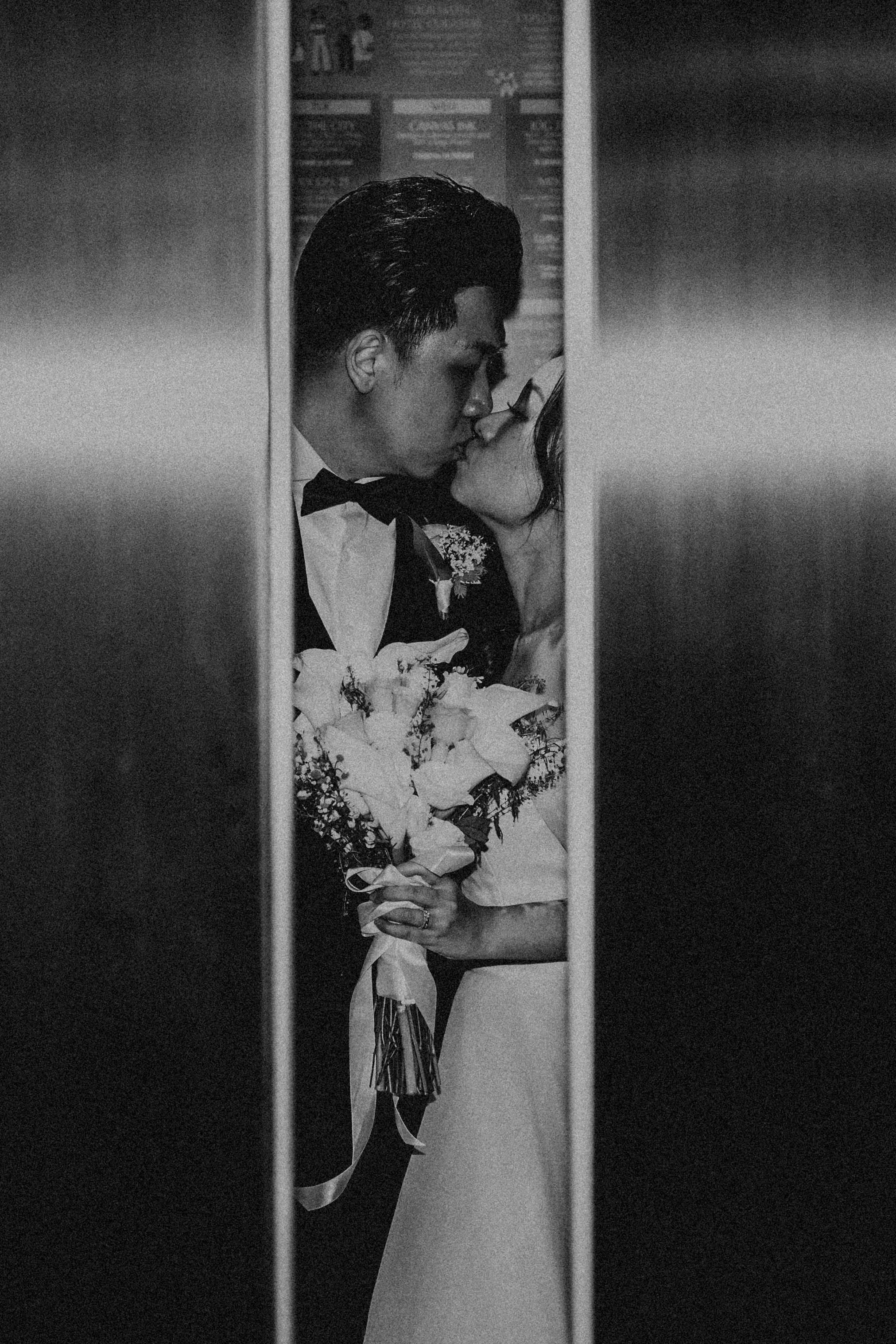 Romantic and cinematic actual day wedding photoshoot of a couple stealing a kiss as the elevator doors are closing, captured by Breadandbutterworks.