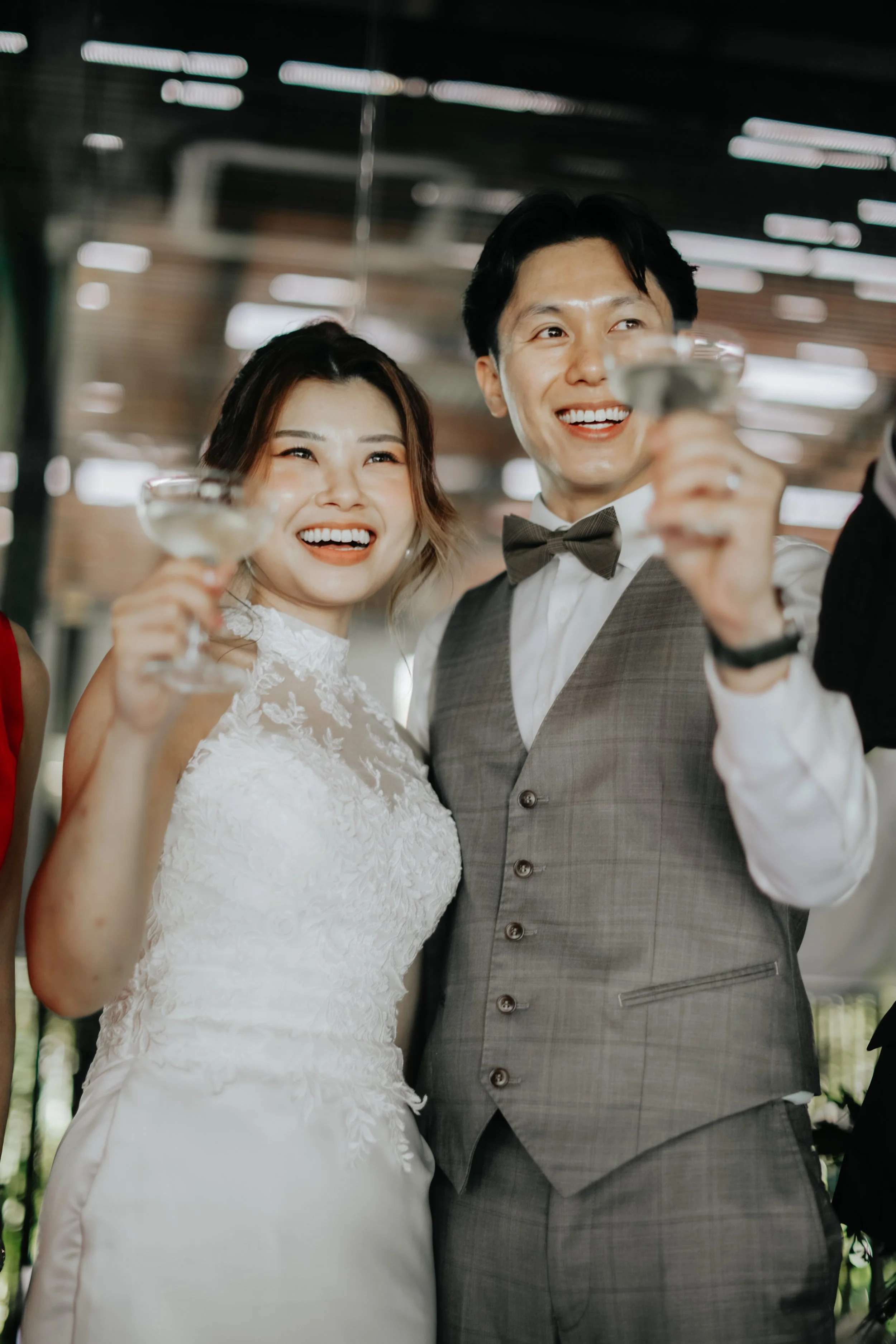 Light and airy actual day wedding photoshoot at Canopy HortPark, the couple holds up their champagne glasses to their guests for a toast. Captured by Arielle from Breadandbutterworks.