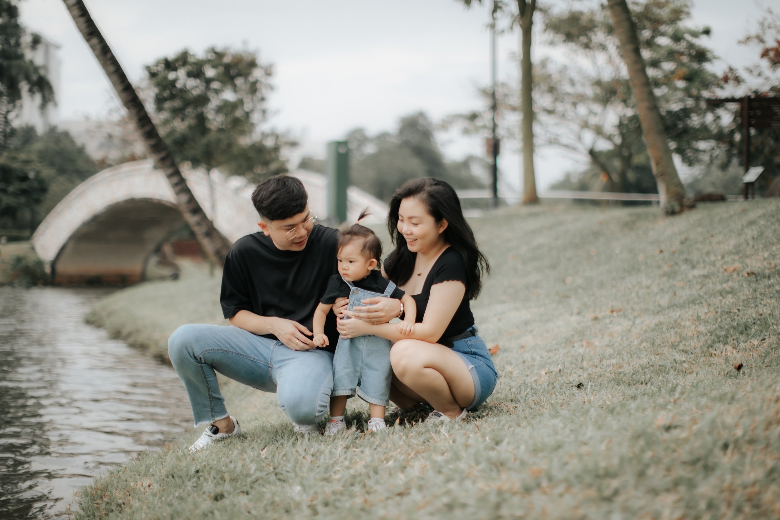 Light and airy family photo of a young family having fun near a body of water in Singapore, captured in a soft outdoor setting in Singapore.