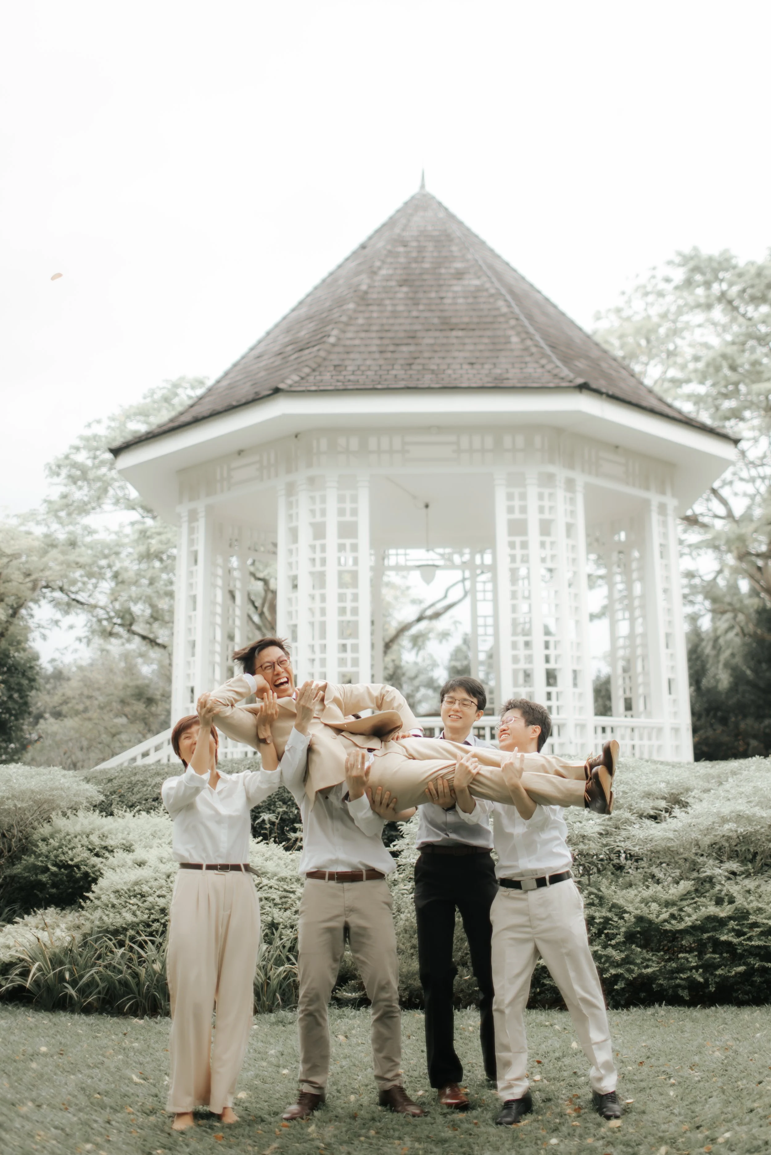 Light and airy actual day wedding photoshoot of the groom and his groomsmen in front of a pavilion. Captured by Arielle for Breadandbutterworks.