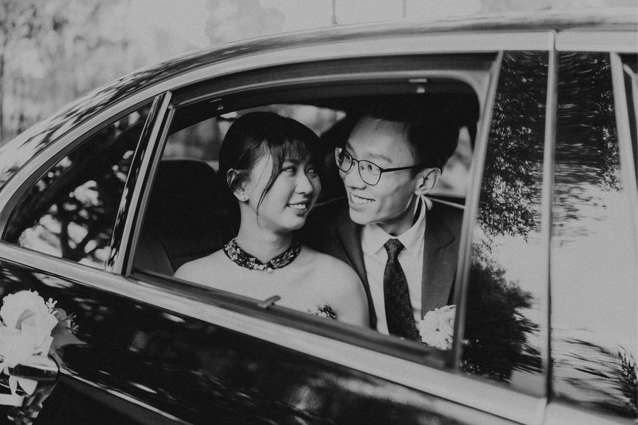 Cinematic black and white photograph of the couple in their wedding car together, about to head to their wedding. Photographed by Breadandbutterworks.