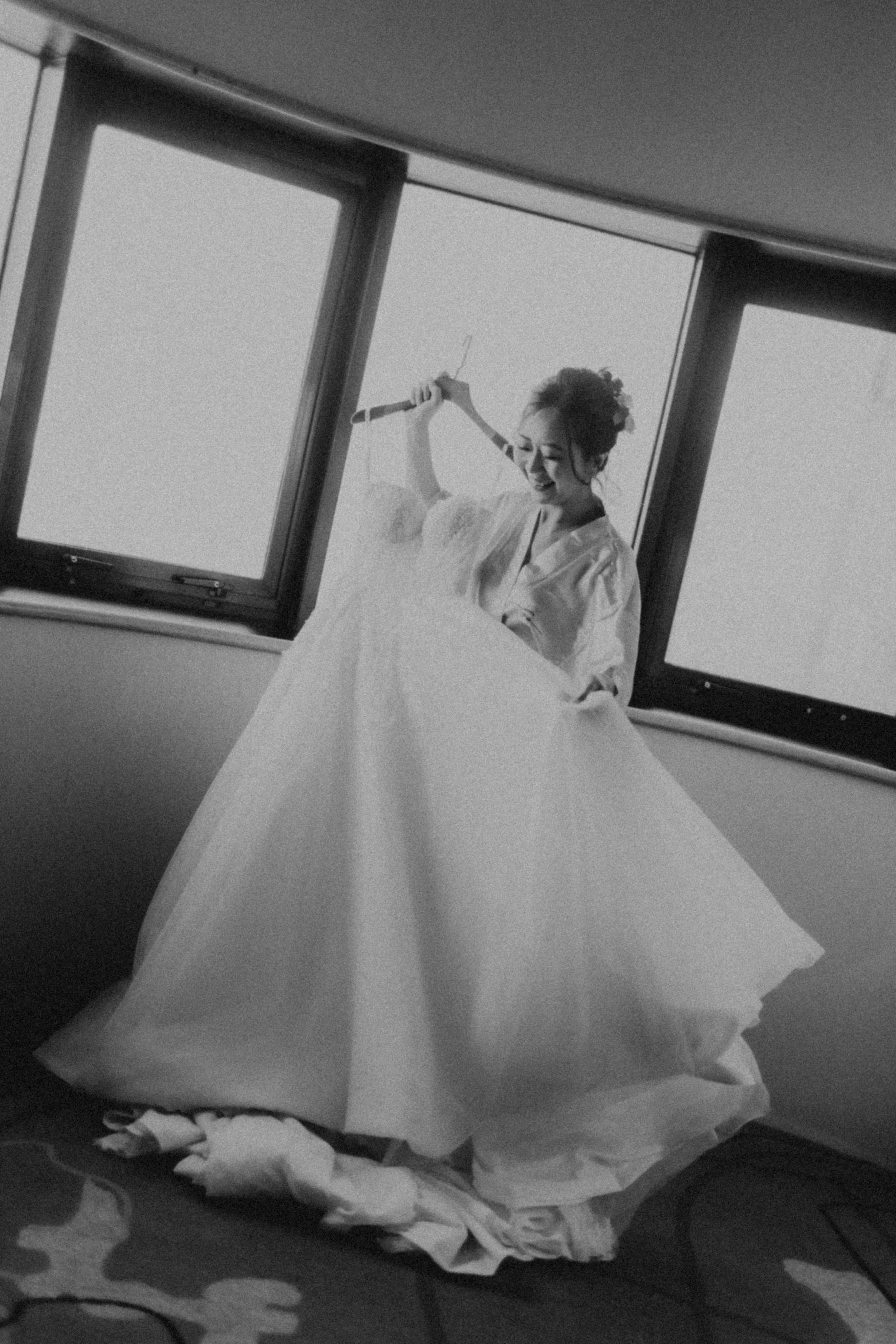 Artistically shot black and white photo of a bride on her actual wedding day moments before she puts on her wedding gown. She beholds her gown lovingly as the image captures the intimate moment. Captured by Arielle for Breadandbutterworks.