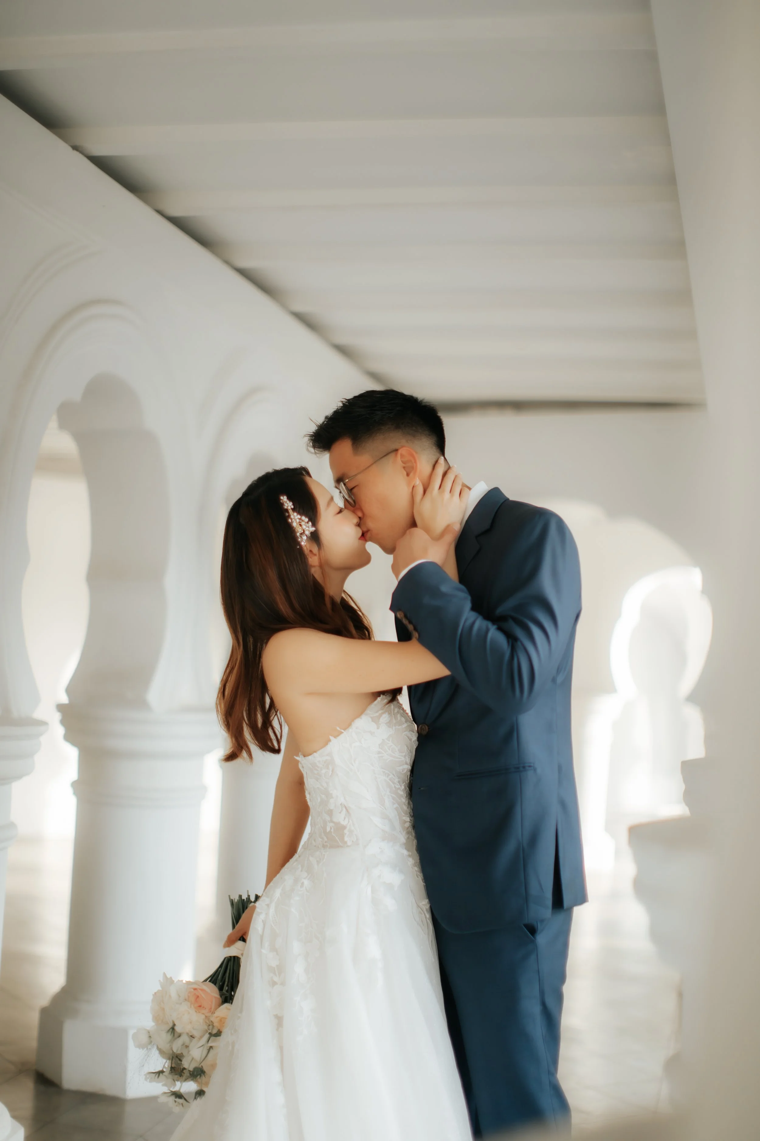Light and airy pre-wedding photoshoot at Arwaa Mansion, featuring the couple sharing a kiss within the colonial architecture. Captured by Ash for Breadandbutterworks.