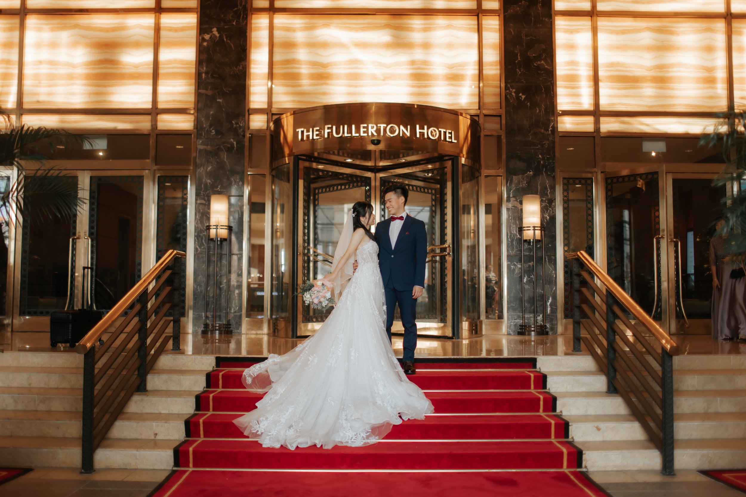 Light and airy actual day wedding photoshoot of the bride and groom standing outside The Fullerton Hotel in Singapore. Captured by Arielle for Breadandbutterworks.