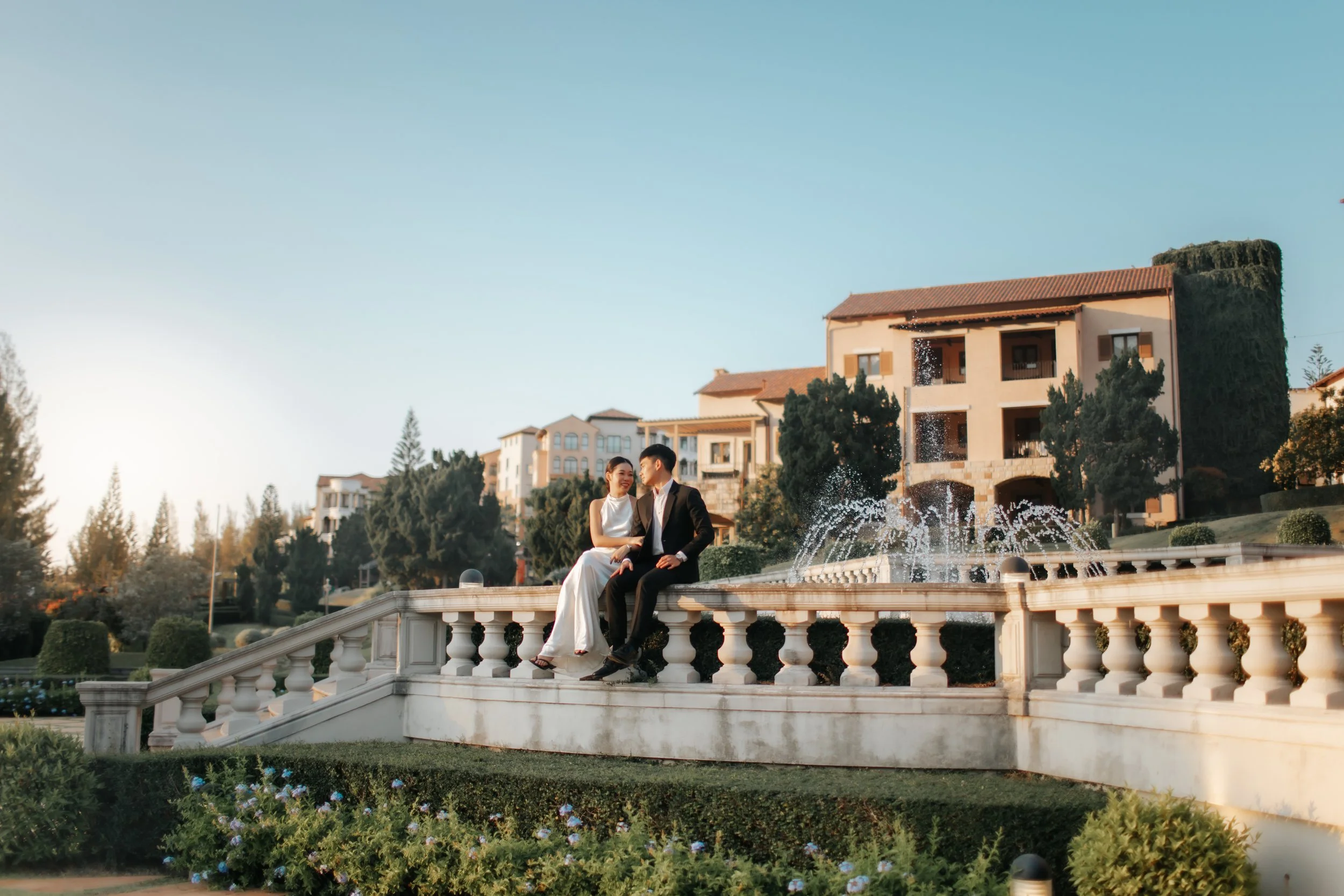 Cover image for Arielle’s overseas pre-wedding photography collection, featuring a couple sitting by a fountain at a scenic garden destination abroad.
