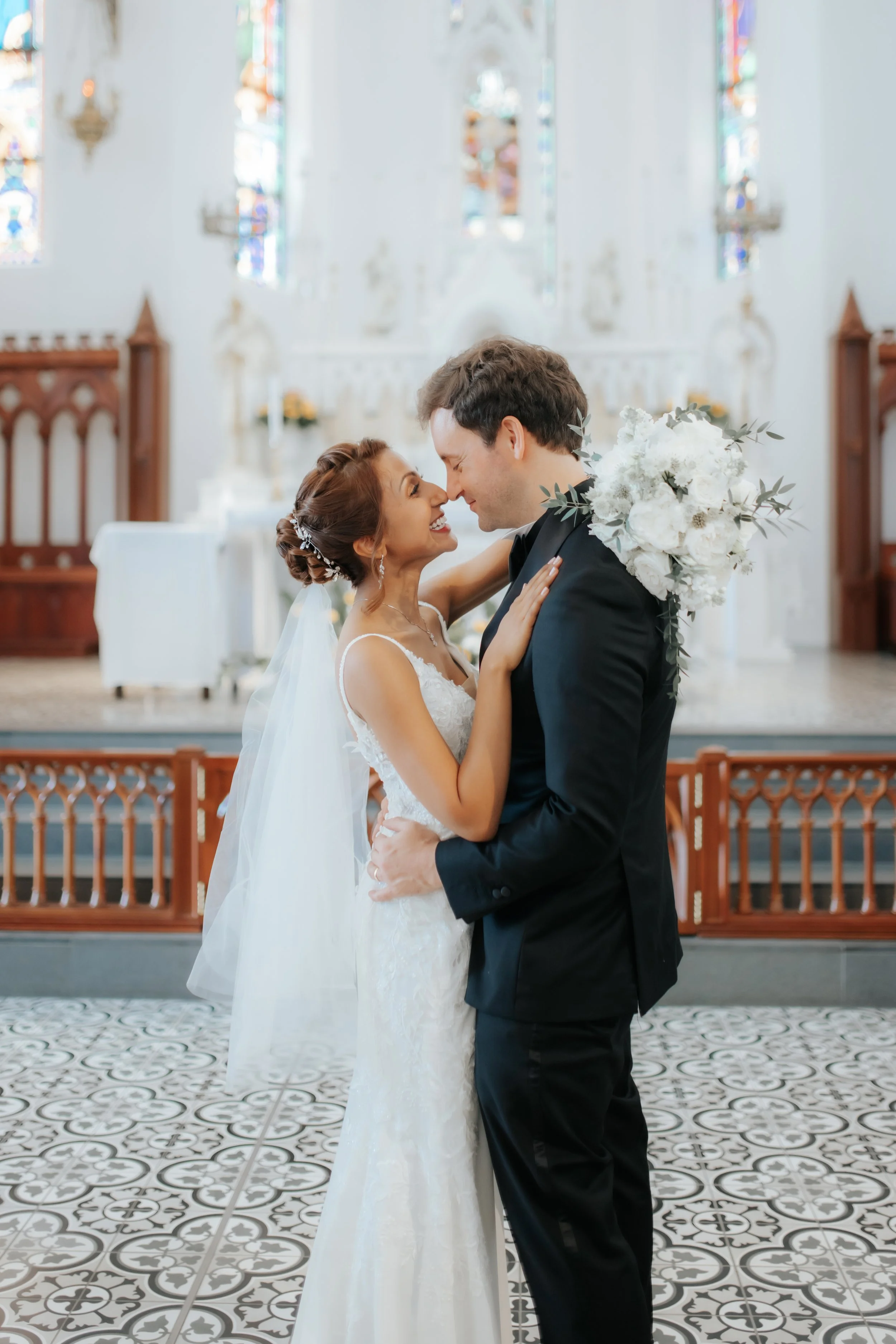 Light and airy actual day church wedding photoshoot at Church of Saints Peter and Paul, the couple shares a romantic moment in front of the lectern captured by Ash for Breadandbutterworks.