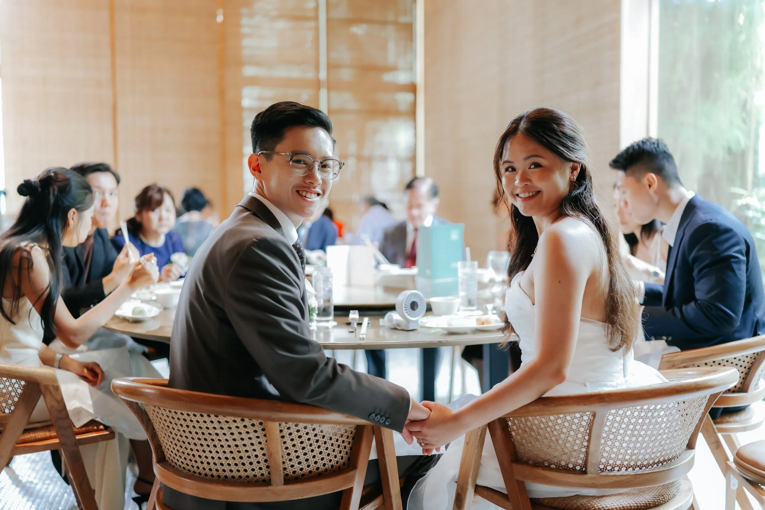 The wedded couple enjoys their meal at a table with their loved ones during their actual day wedding. Photographed by Breadandbutterworks.