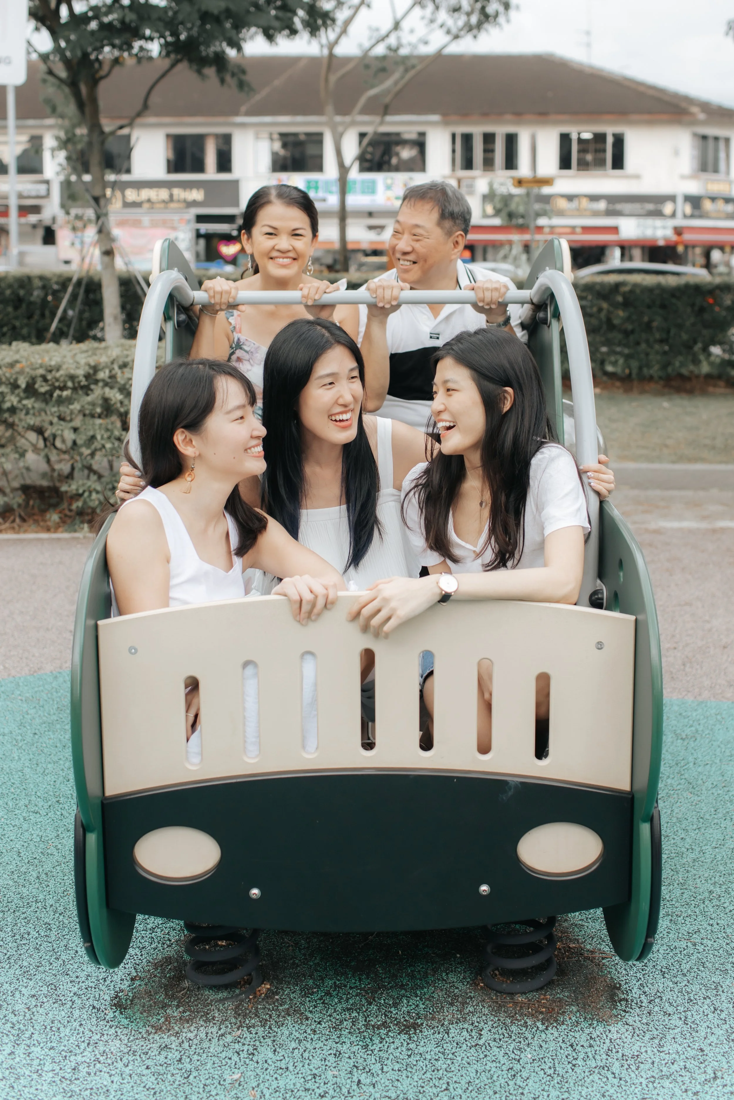 Heartwarming family photoshoot in Singapore featuring a family posing in a playground, captured in a light and airy style by Arielle for Breadandbutterworks.