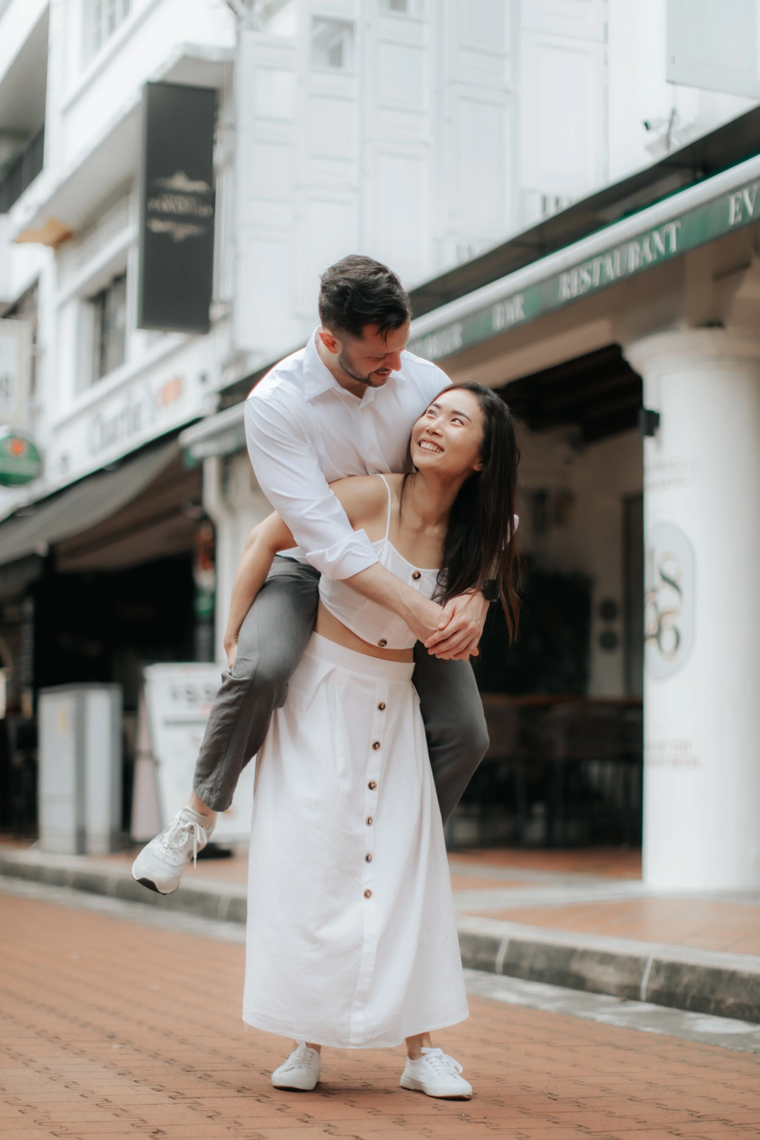 Light and airy proposal photoshoot at Anderson Bridge, the couple playfully poses with the bride-to-be piggy backing her fiance. Captured by Arielle for Breadandbutterworks.