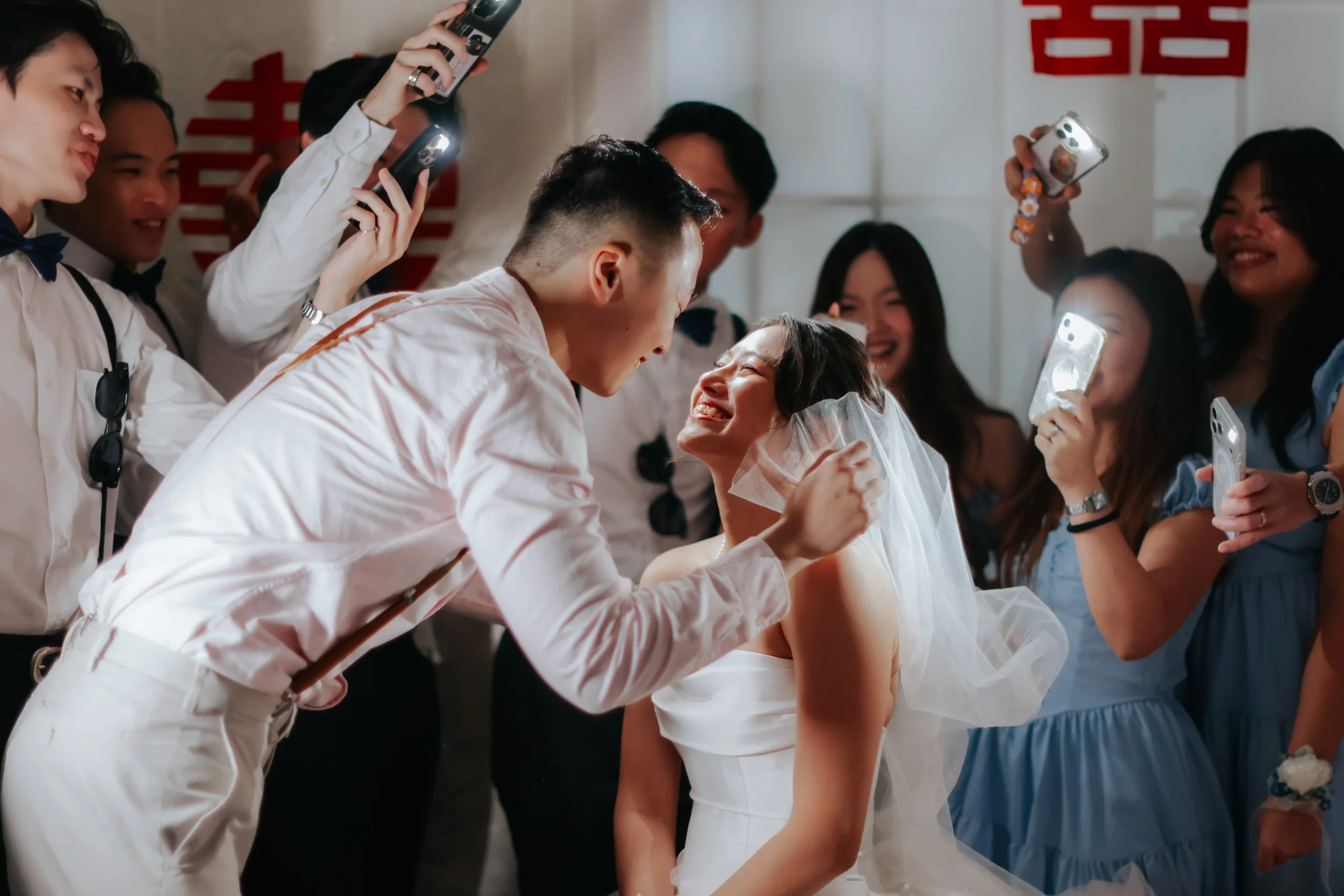 Joyful actual day wedding photography of the couple sharing their first look as the groom lifts the bride's veil, captured by Breadandbutterworks in a soft and heartfelt style.