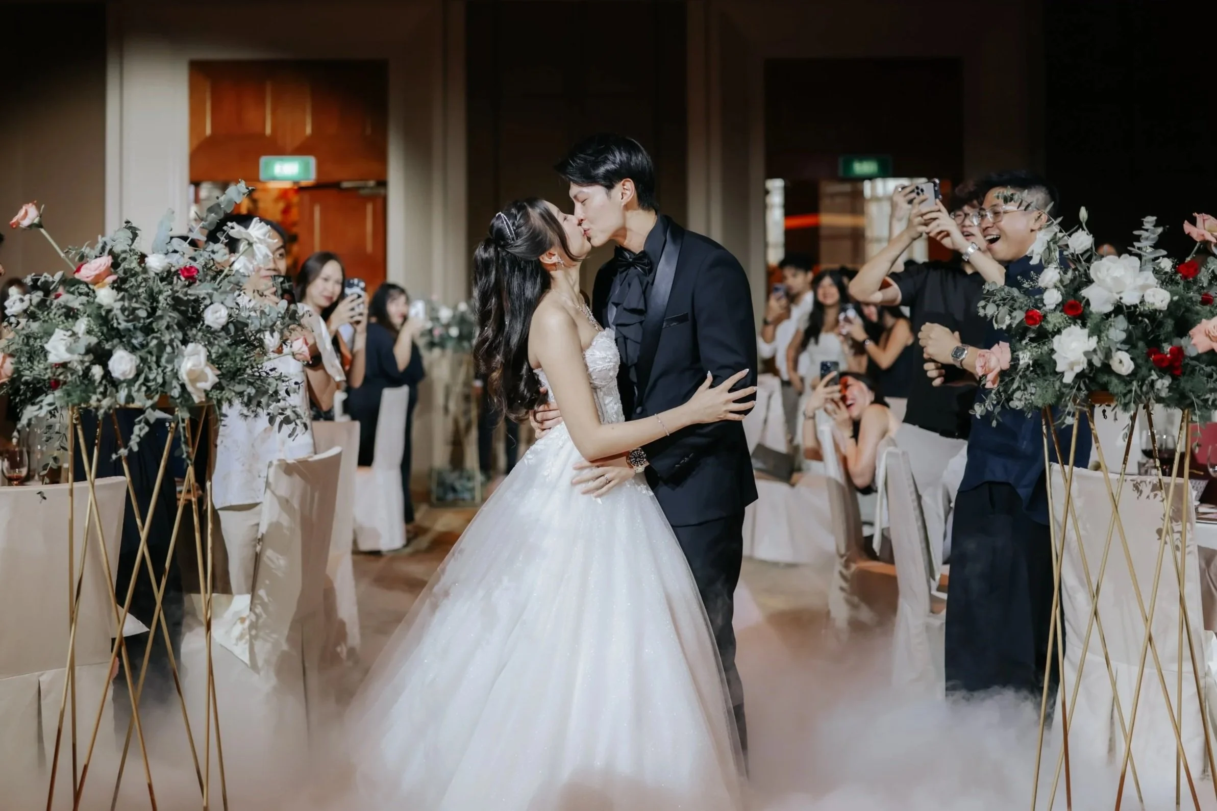 Cover image for Ash’s actual day wedding photography collection, featuring a couple sharing a kiss during their wedding march-in in Singapore.