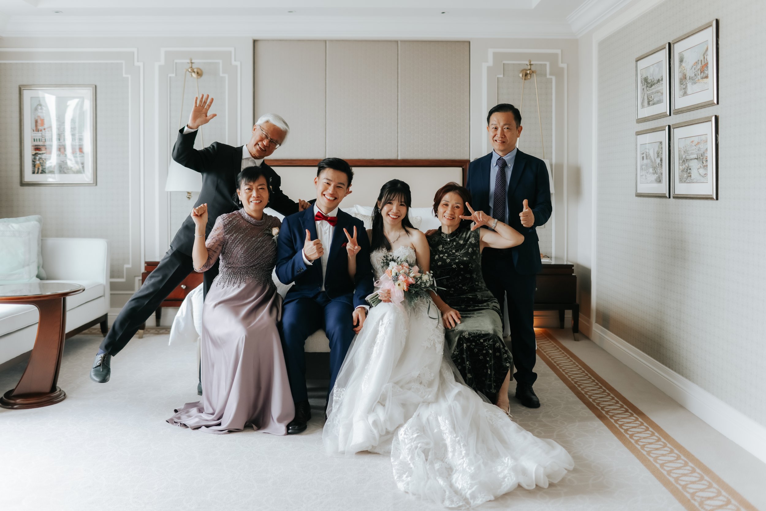 The bride and groom with their immediate families posing for a fun photo during their actual day wedding in the hotel suite before their entrance to the venue. Captured in a light and airy style by Arielle for Breadandbutterworks.