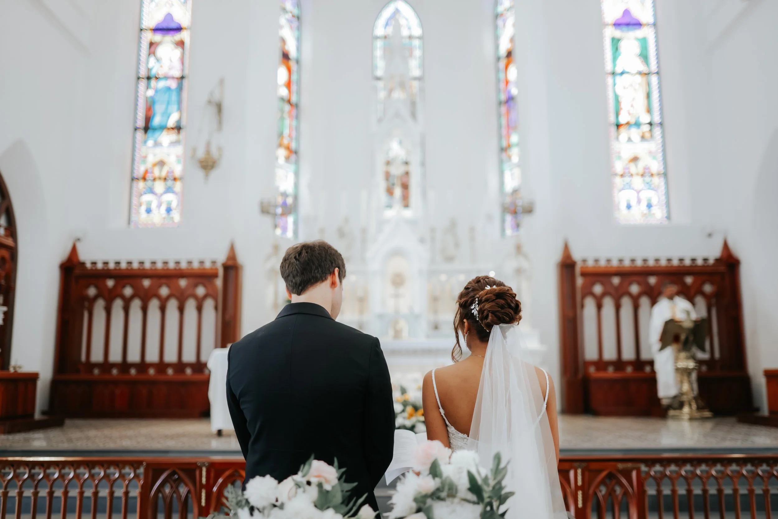 Light and airy actual day church wedding photoshoot at Church of Saints Peter and Paul, the couple shares a romantic moment in front of the lectern captured by Ash for Breadandbutterworks.