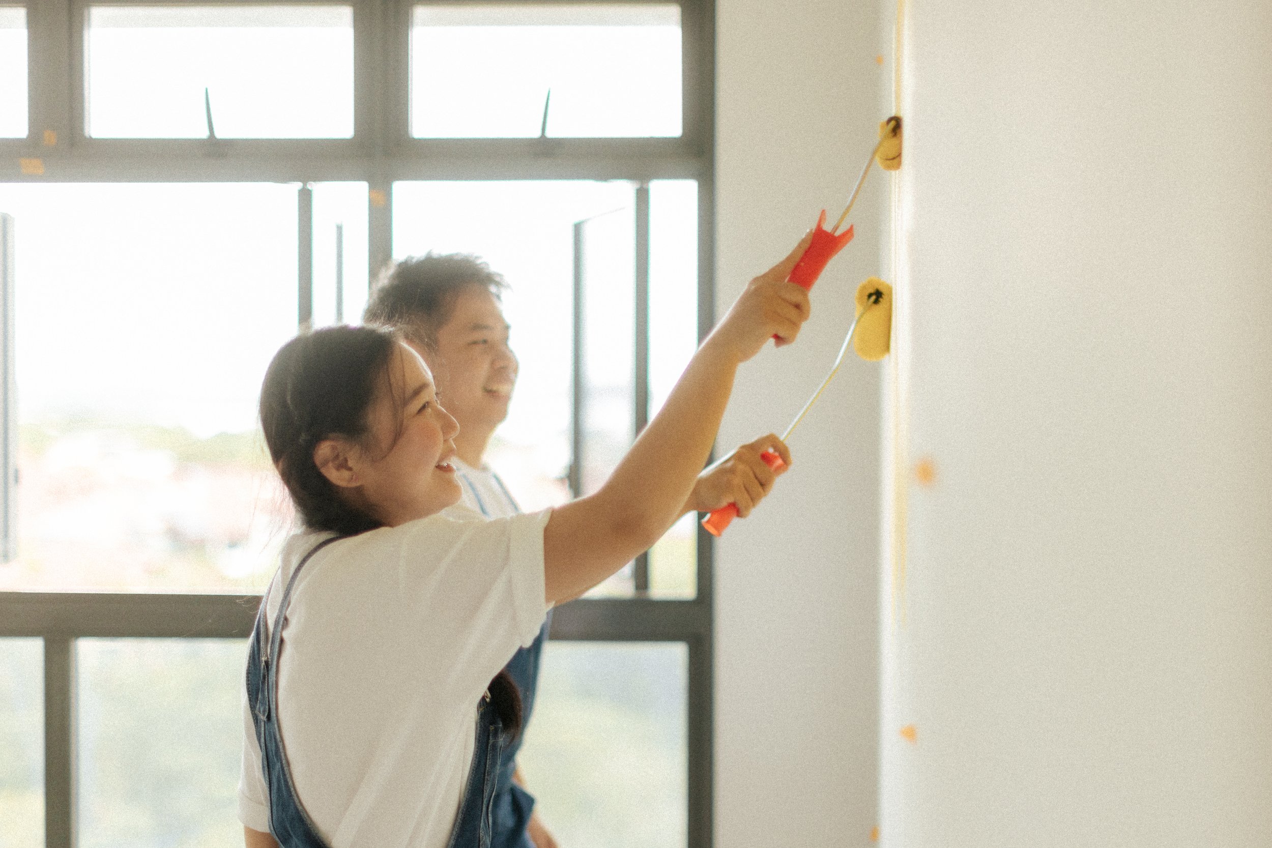 Playful home pre-wedding photo of a couple painting their marital home together, captured by Breadandbutterworks in a light, airy and heartfelt style.