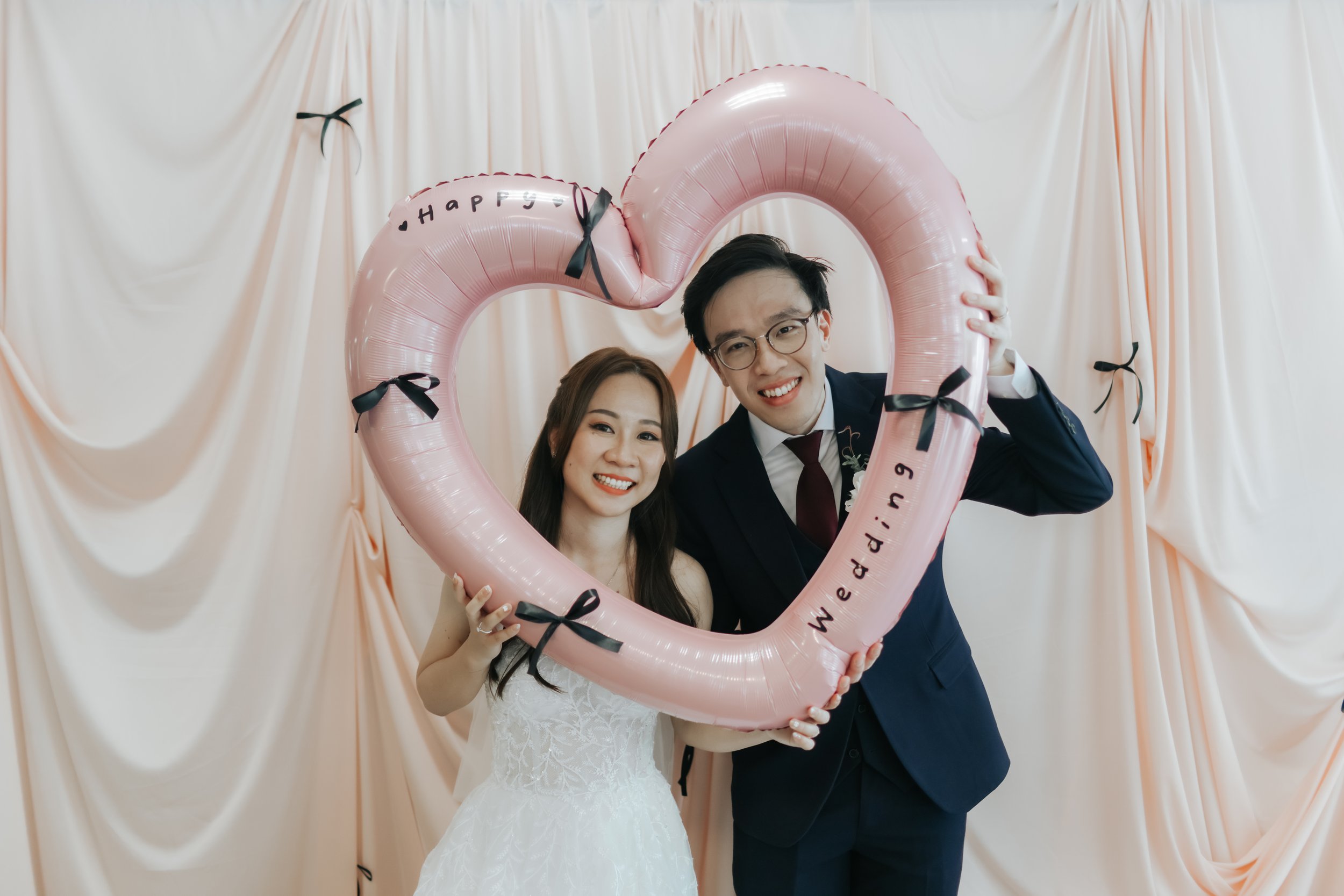 Light and airy actual day photoshoot of a couple posing with a heart-shaped balloon. Captured by Arielle for Breadandbutterworks.